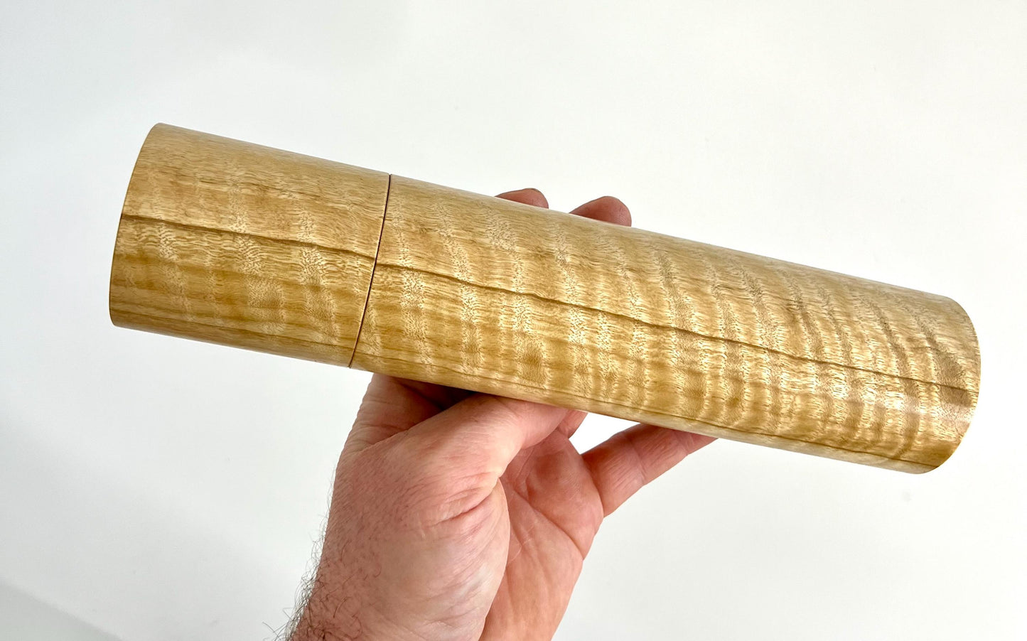 Mans hand holding single straight cylindrical Narrow leaf peppermint timber grinder
