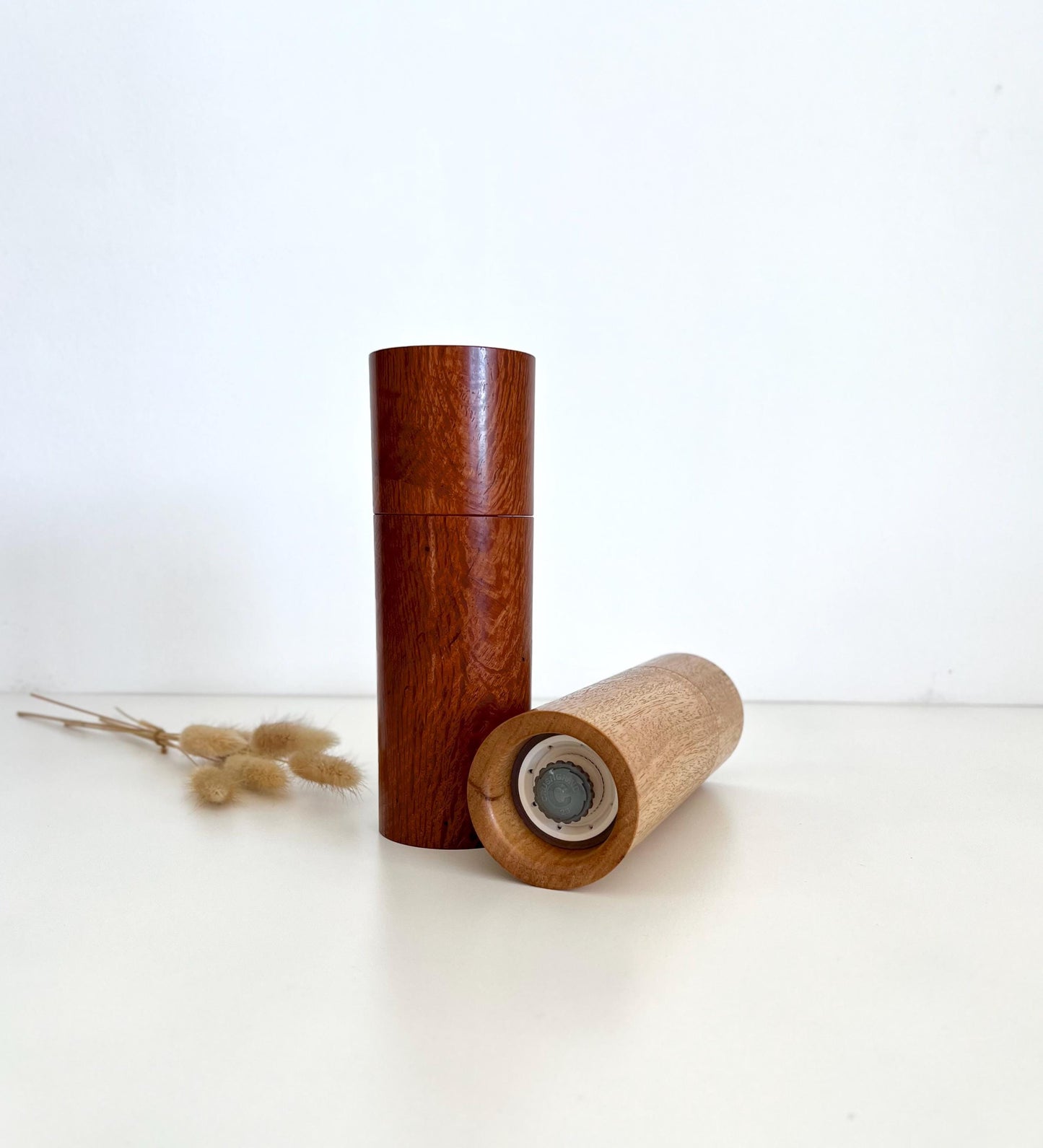 Mans hand holding single straight cylindrical Blackbutt timber grinder