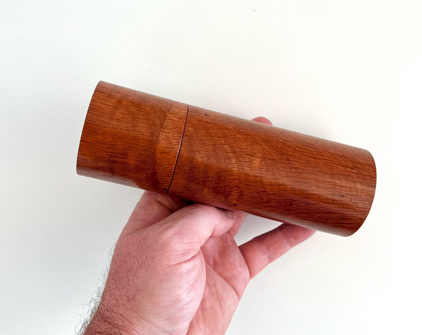Mans hand holding single straight cylindrical Sheoak timber grinder