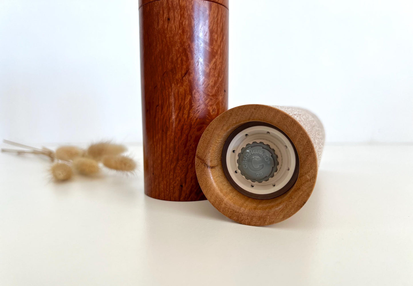 Mans hand holding single straight cylindrical Blackbutt timber grinder
