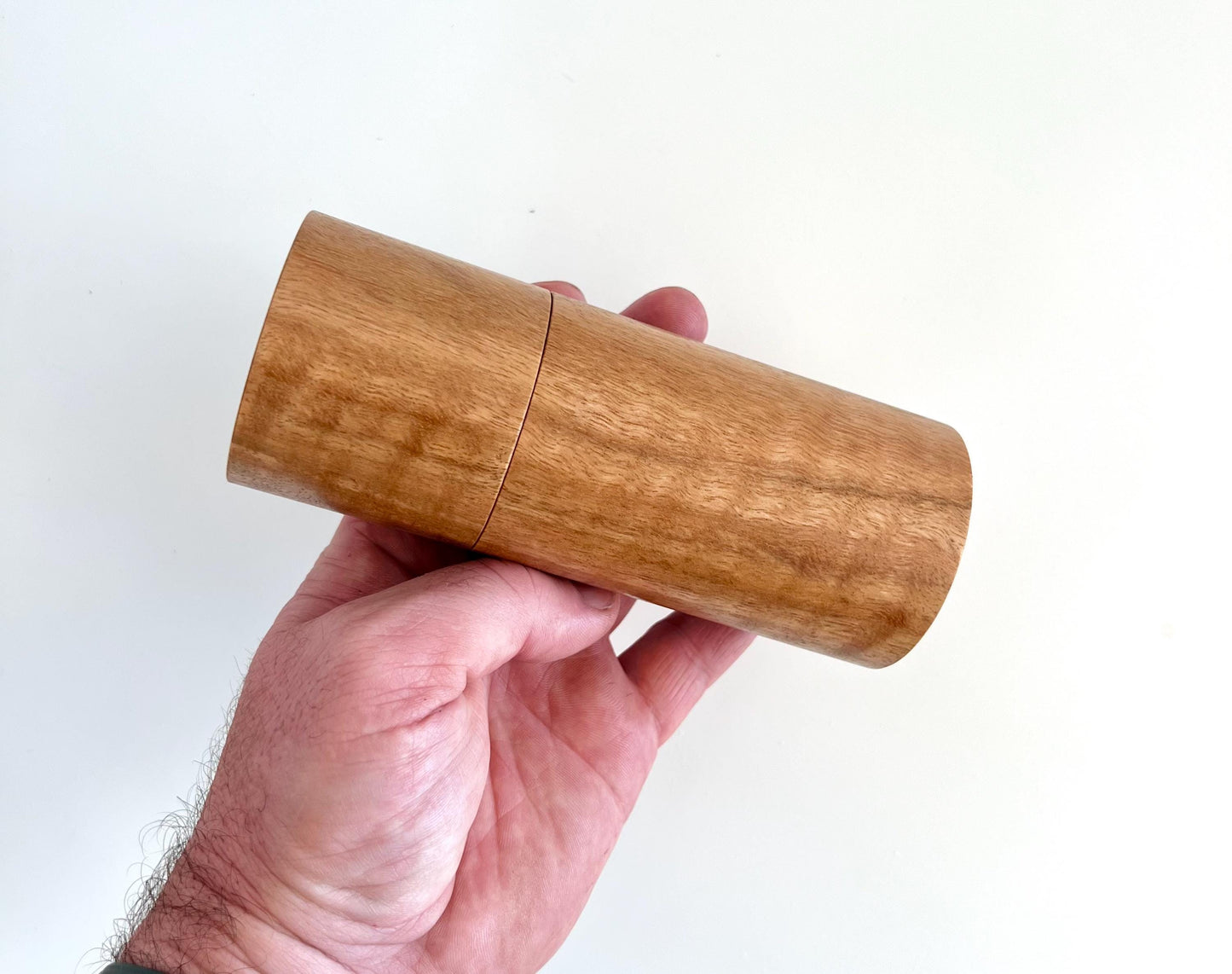 Mans hand holding single straight cylindrical Marri timber grinder