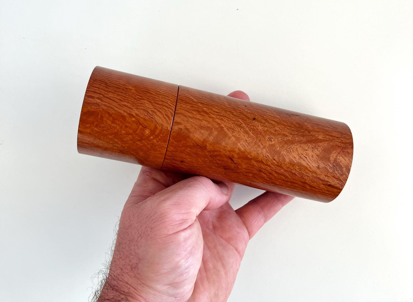 Mans hand holding single straight cylindrical Sheoak timber grinder
