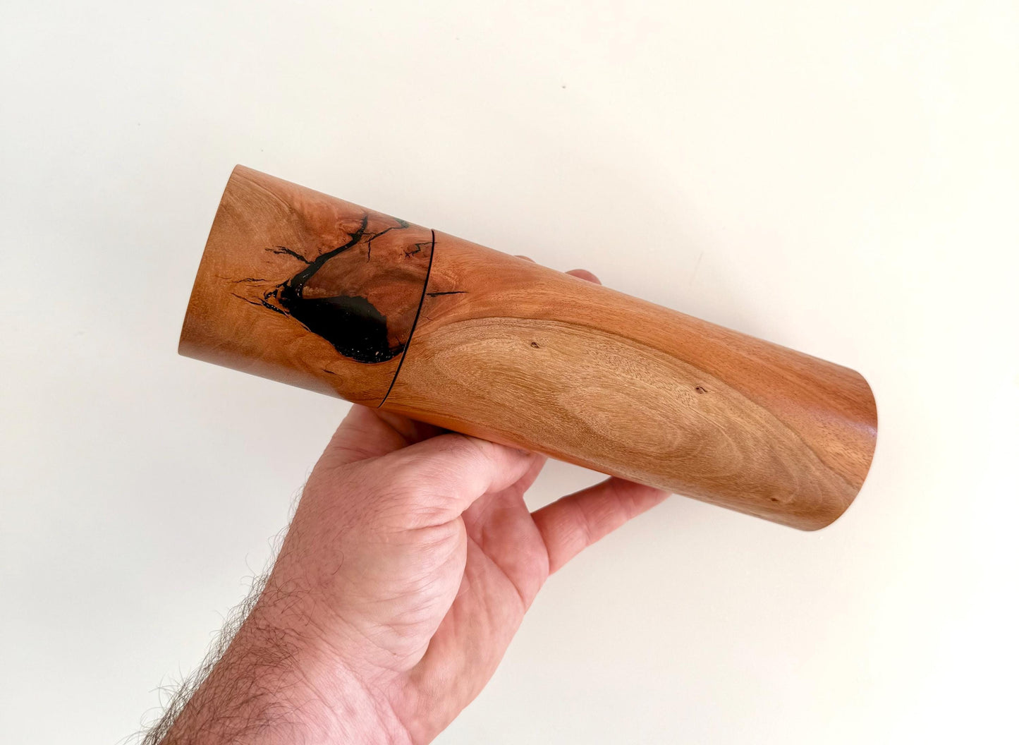 Mans hand holding single straight cylindrical river red gum timber grinder