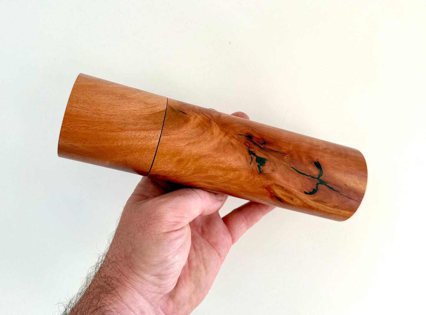 Mans hand holding single straight cylindrical river red gum timber grinder