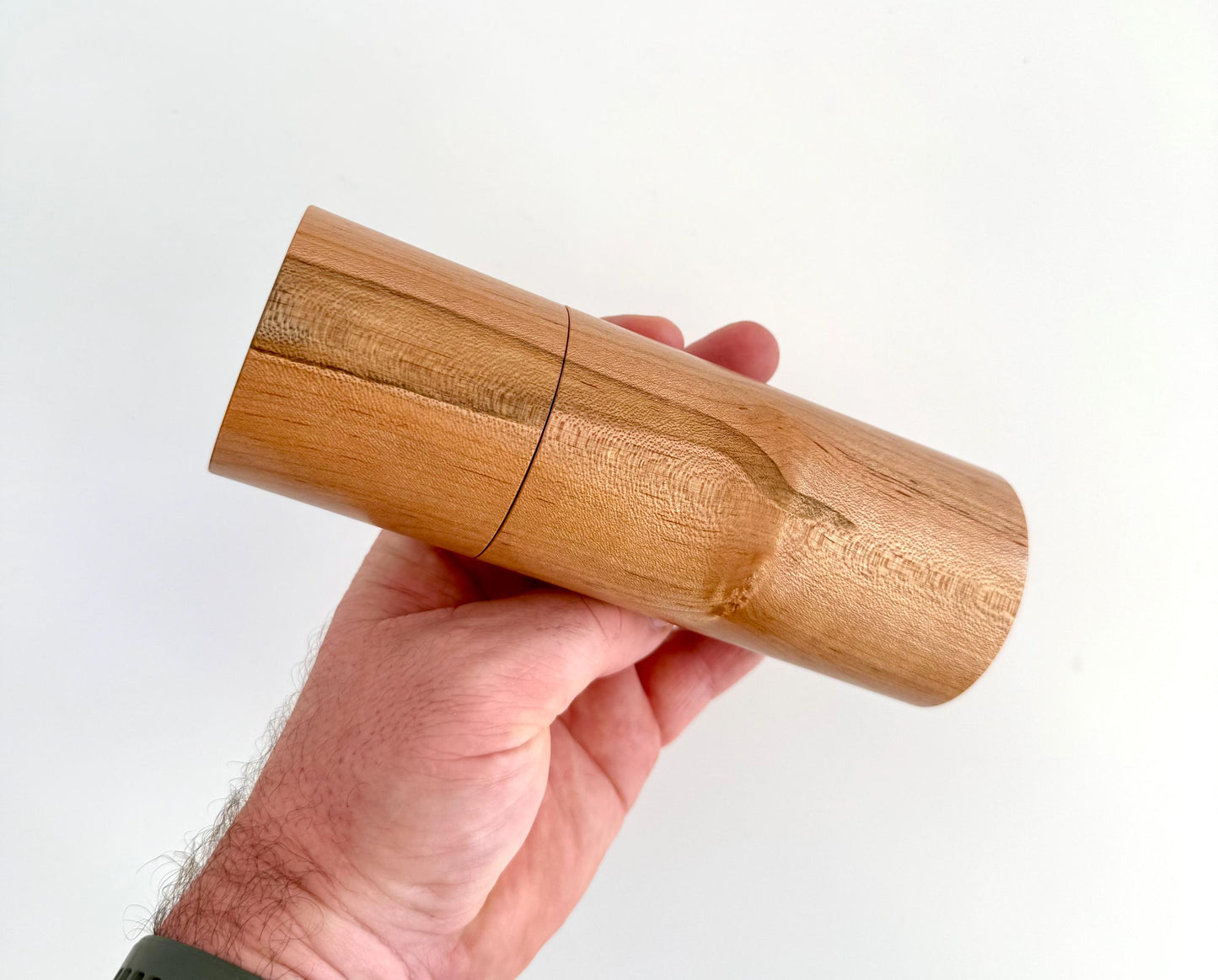 Mans hand holding single straight Maple grinder