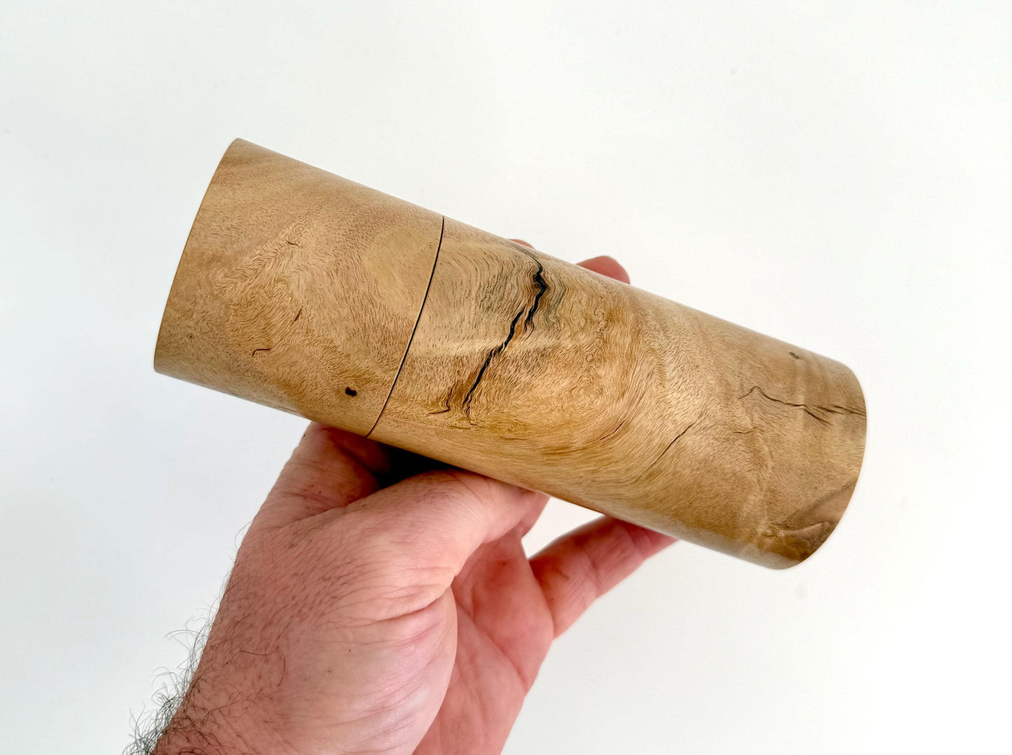 Mans hand holding single straight cylindrical Lemon scented gum timber grinder