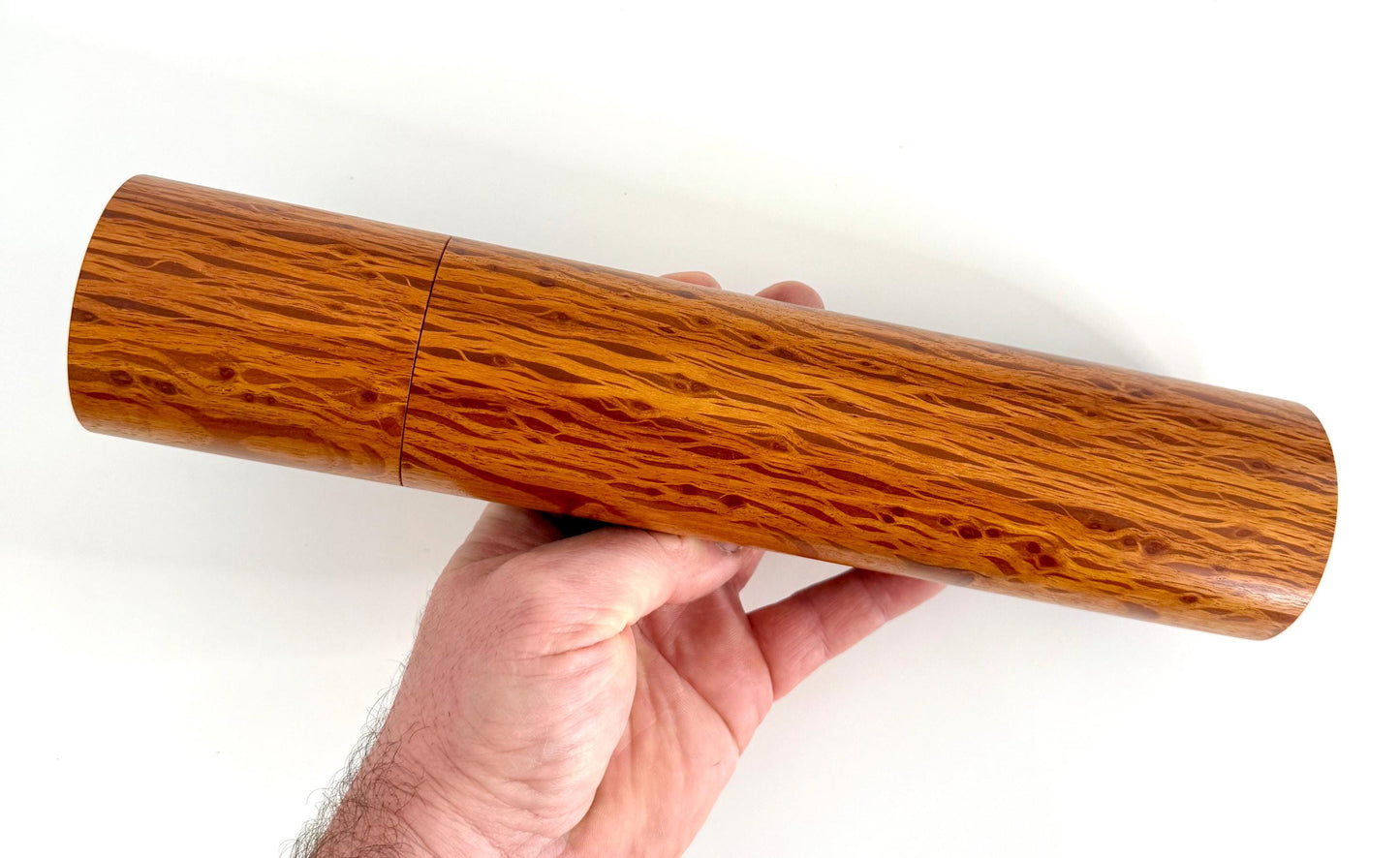 Mans hand holding single straight cylindrical Sheoak timber grinder