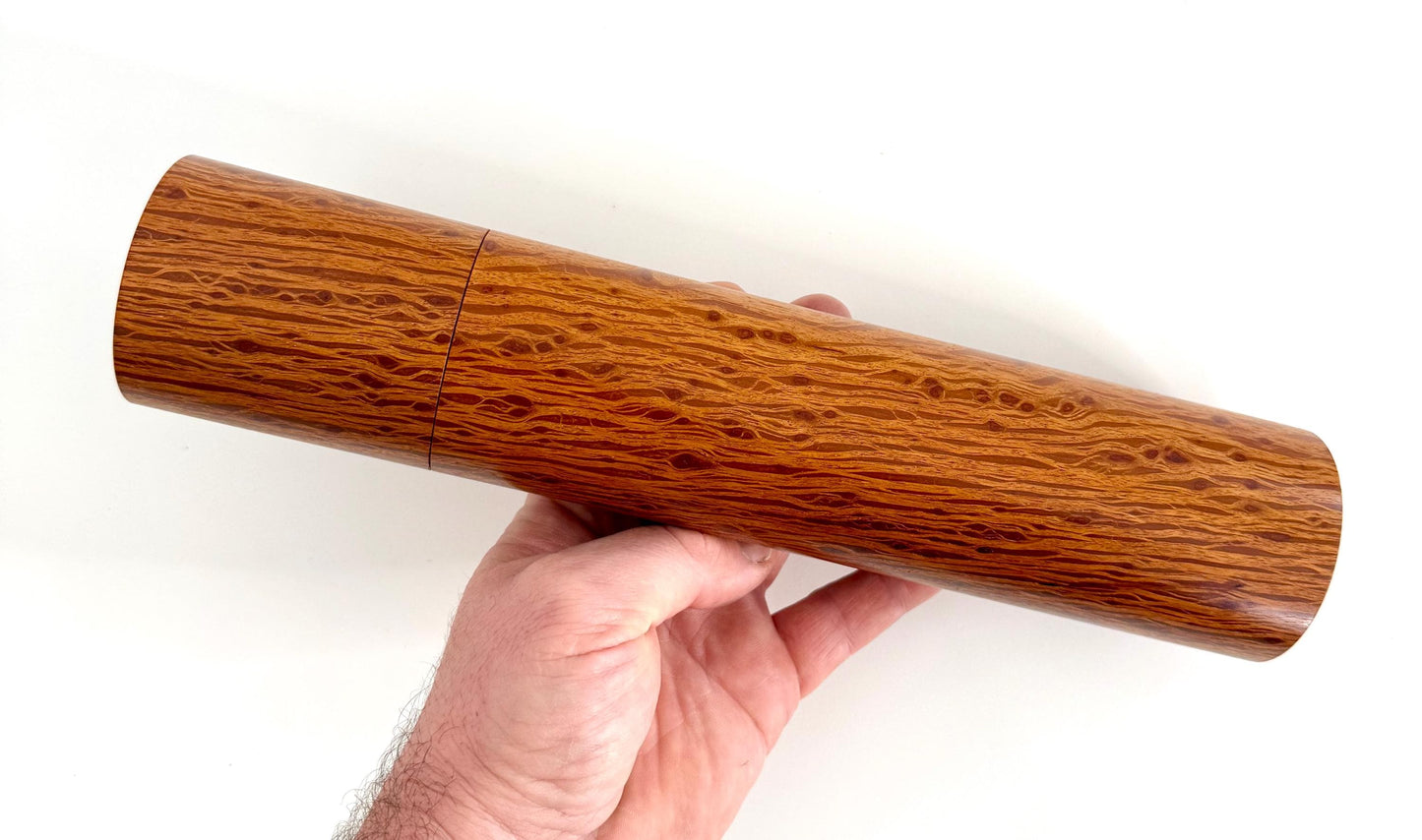 Mans hand holding single straight cylindrical Sheoak timber grinder