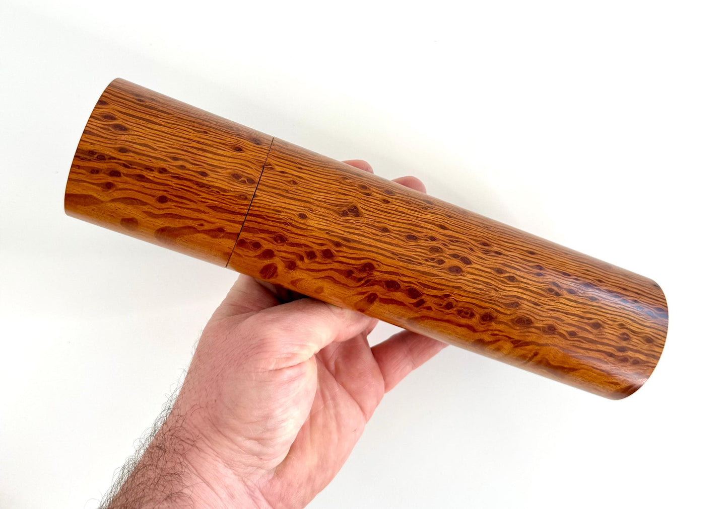 Mans hand holding single straight cylindrical Sheoak timber grinder