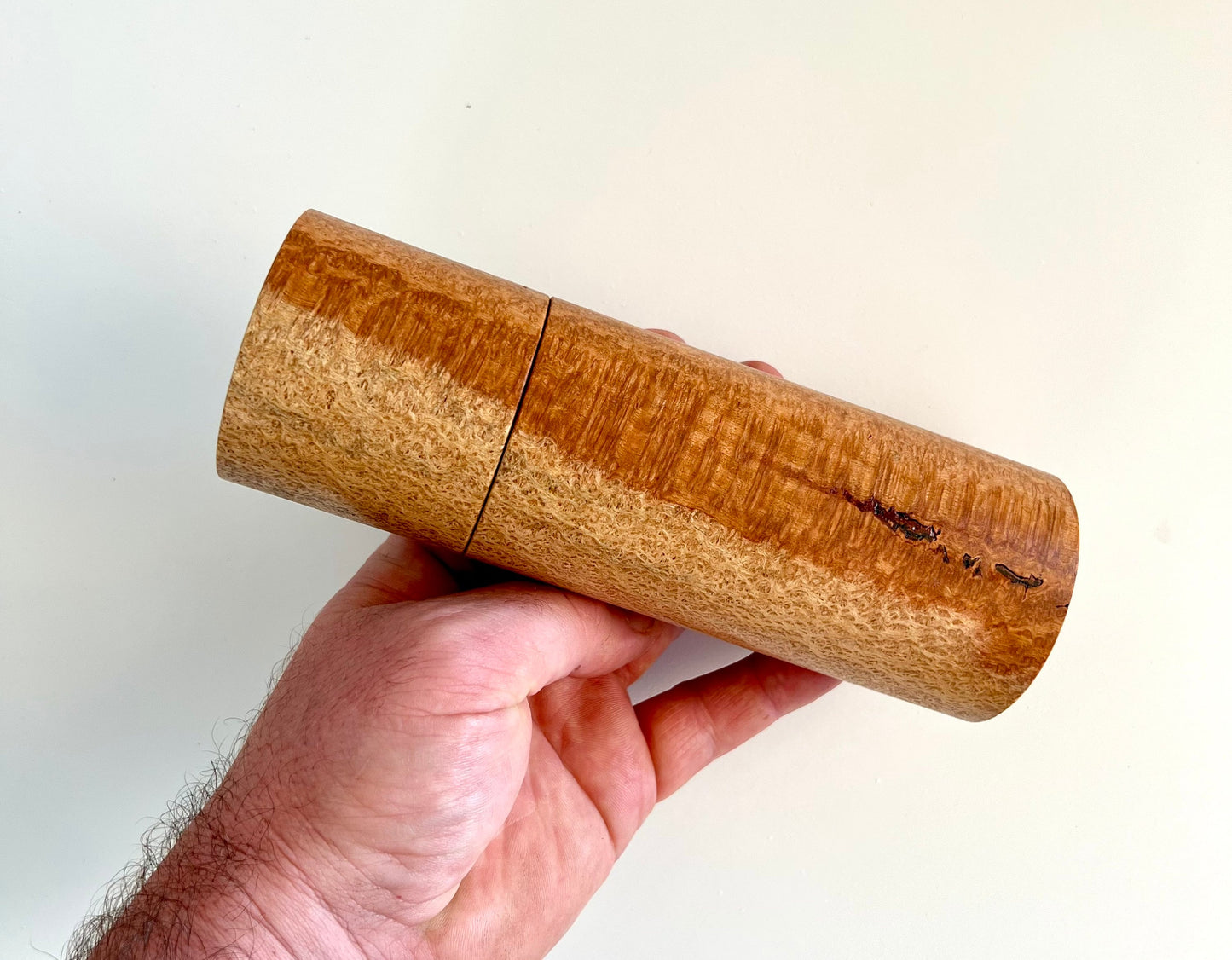 Mans hand holding single straight cylindrical Snotty Gobble grinder
