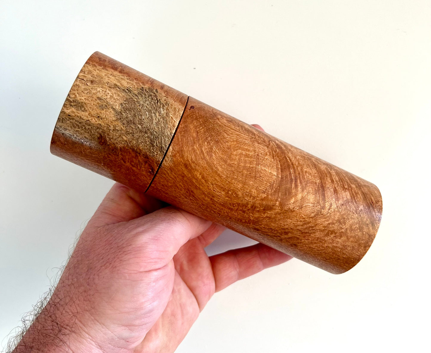 Mans hand holding single straight cylindrical Snotty Gobble grinder