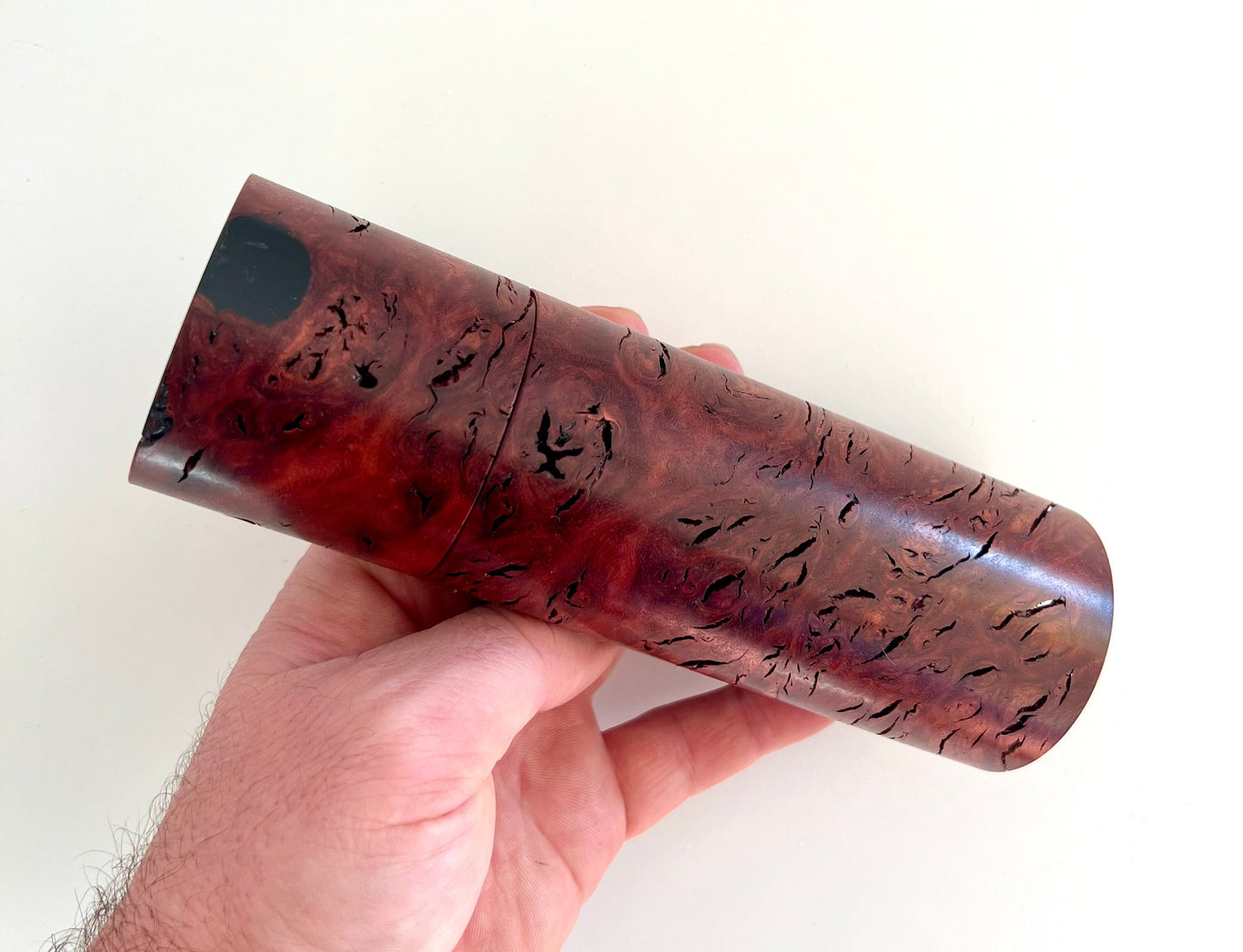 Mans hand holding single straight cylindrical Jarrah Burl grinder