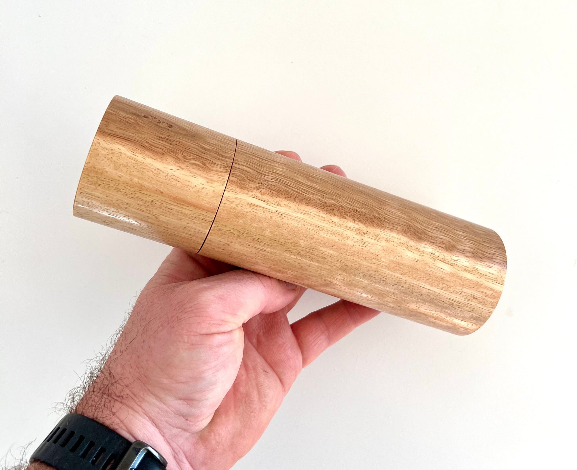 Mans hand holding single straight cylindrical Tasmanian blue gum timber grinder