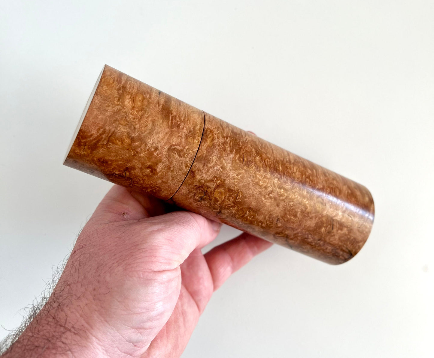 Mans hand holding single straight cylindrical Sugar gum timber grinder