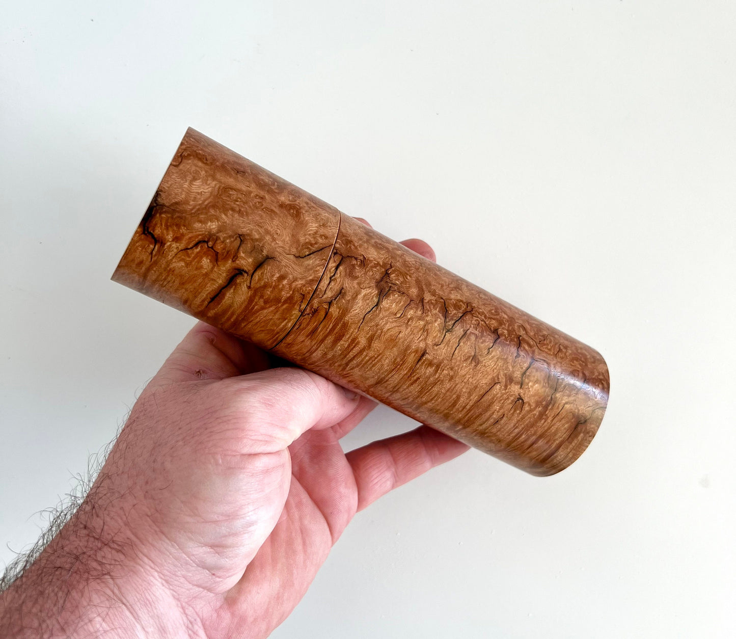 Mans hand holding single straight cylindrical Sugar gum timber grinder