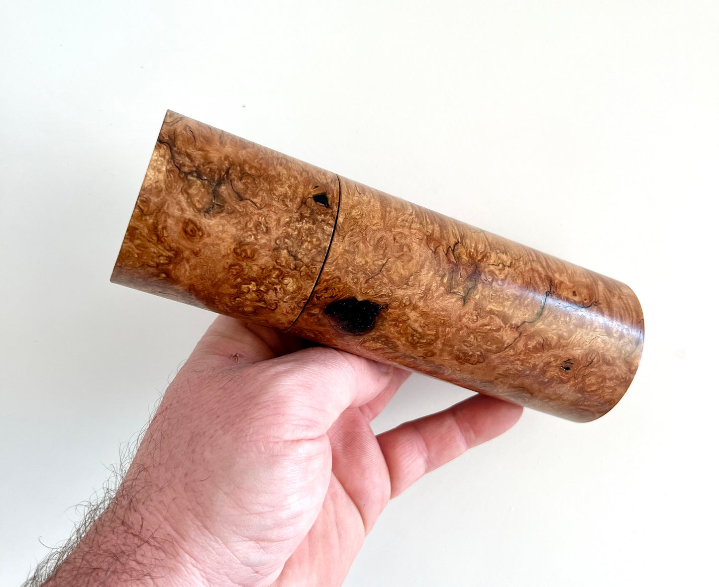 Mans hand holding single straight cylindrical Sugar gum timber grinder