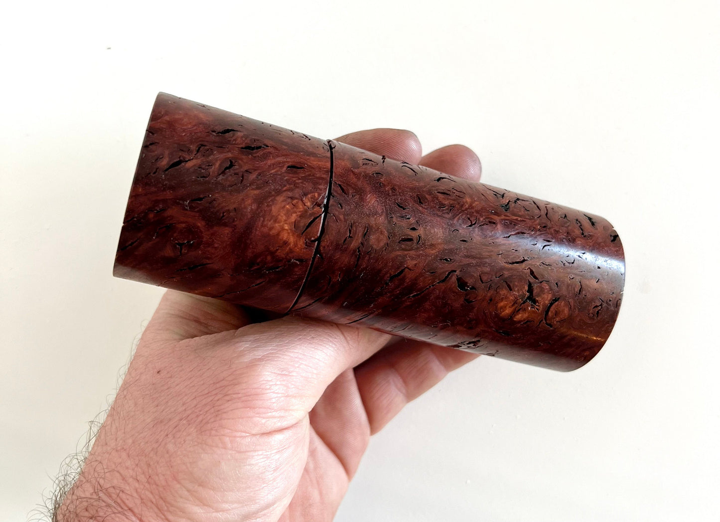 Mans hand holding single straight cylindrical jarrah burl grinder.