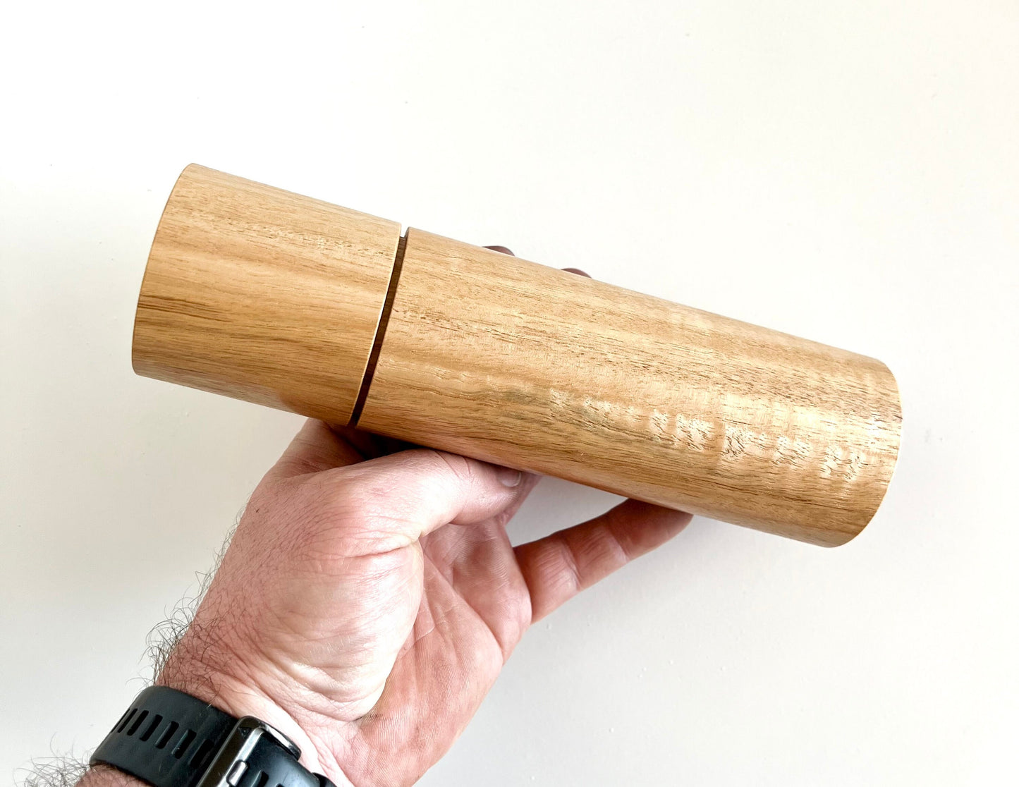 Mans hand holding single straight cylindrical Blackbutt grinder.