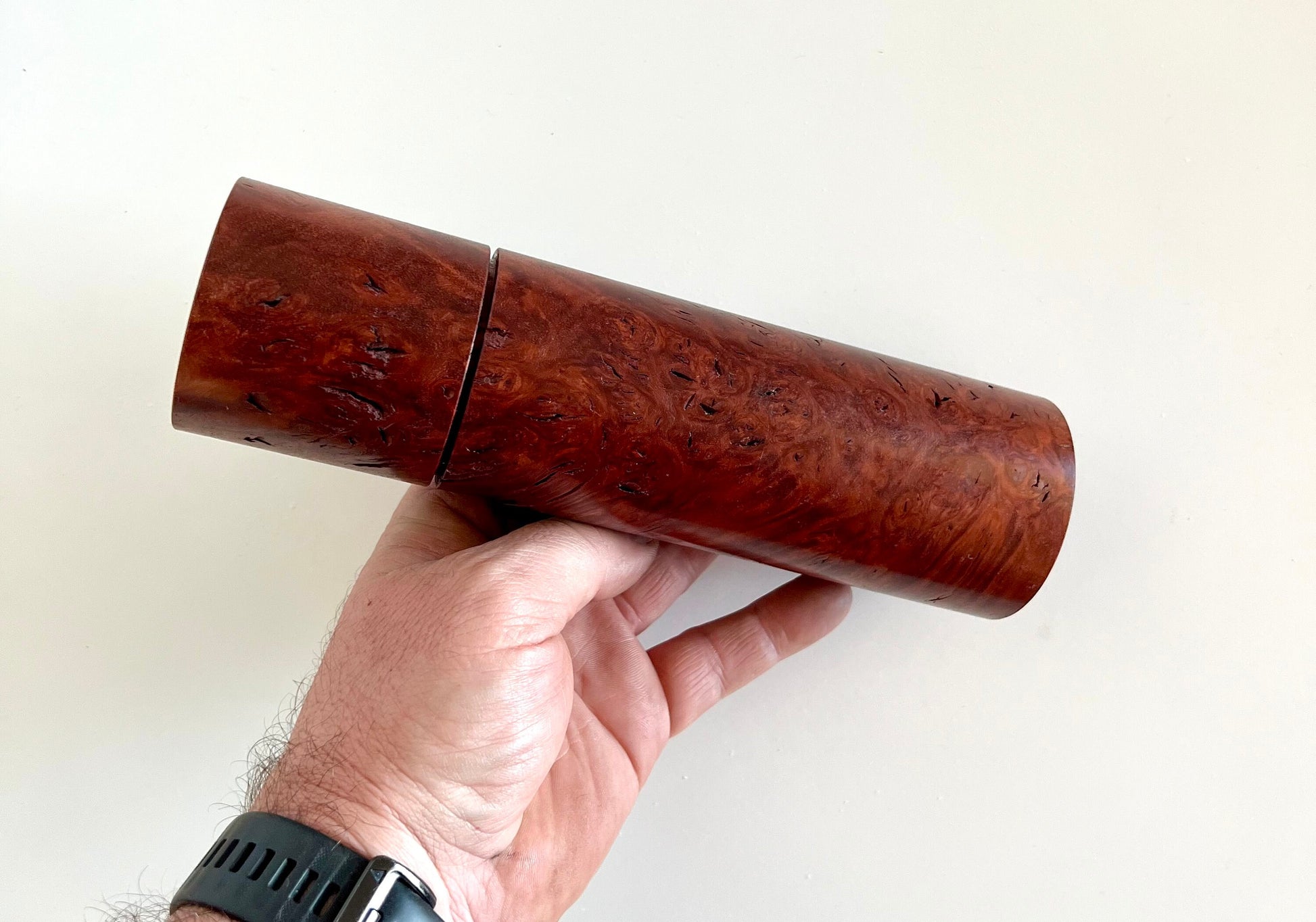 Mans hand holding single straight cylindrical Jarrah burl grinder.