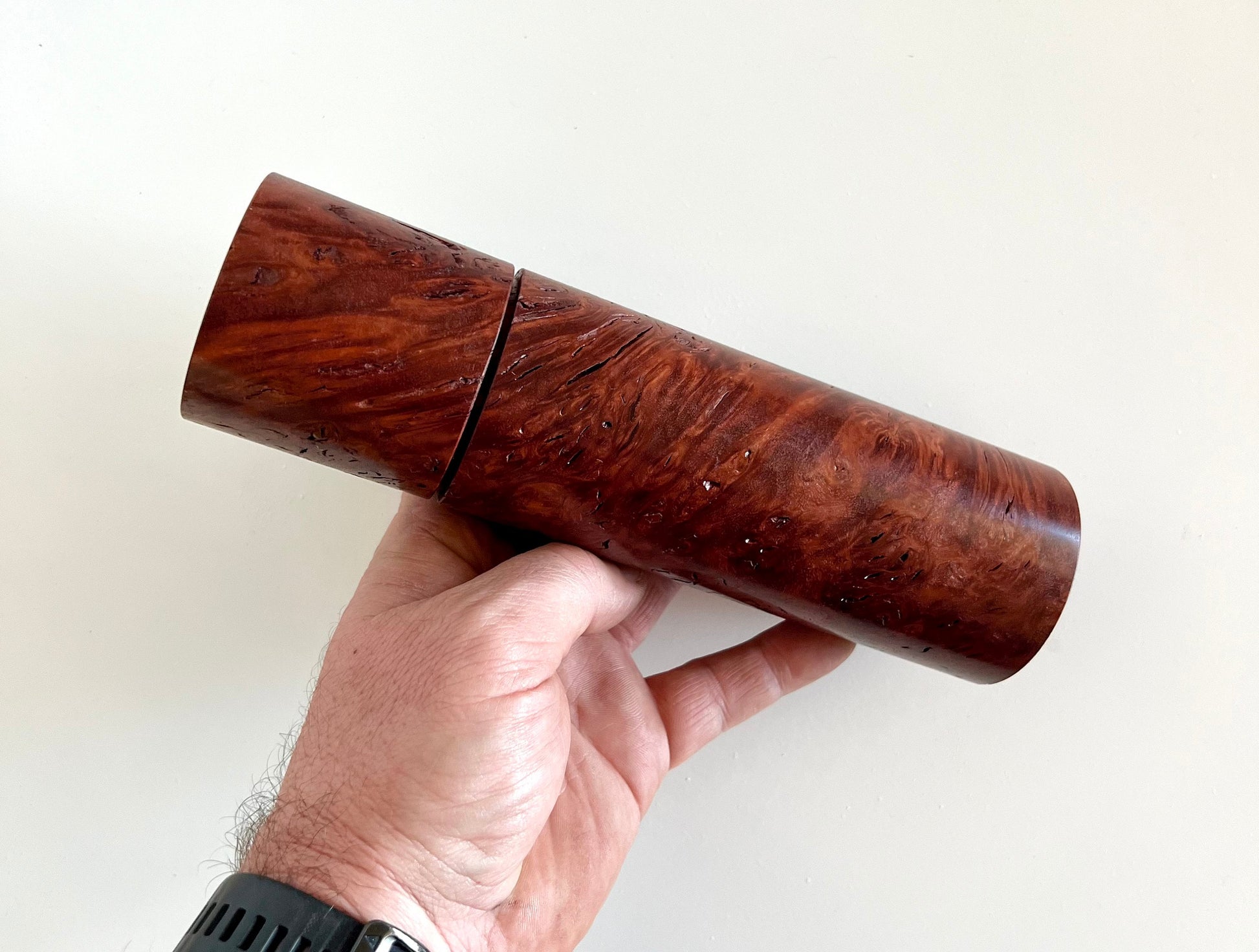 Mans hand holding single straight cylindrical Jarrah burl grinder.