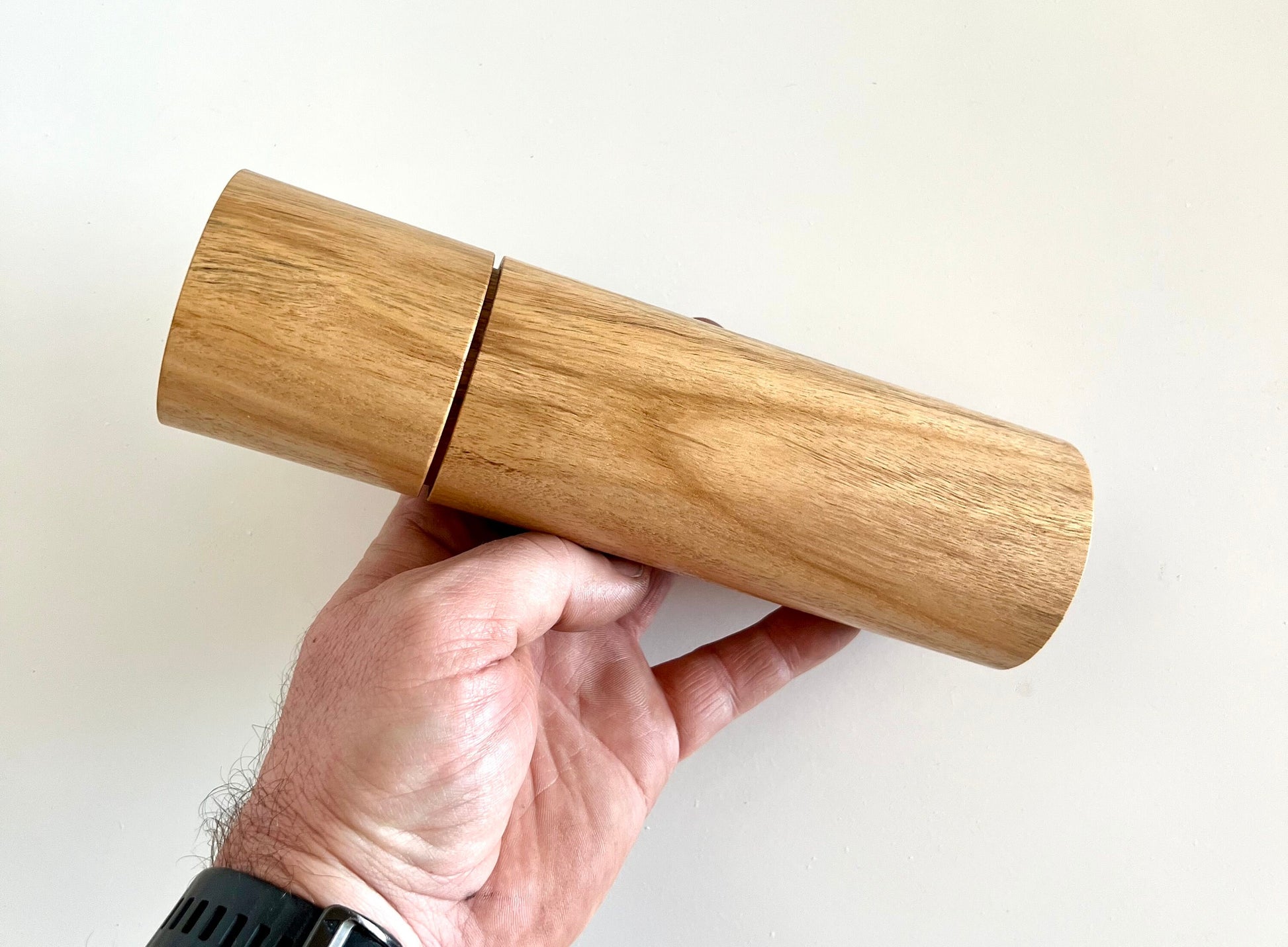 Mans hand holding single straight cylindrical Blackbutt grinder.