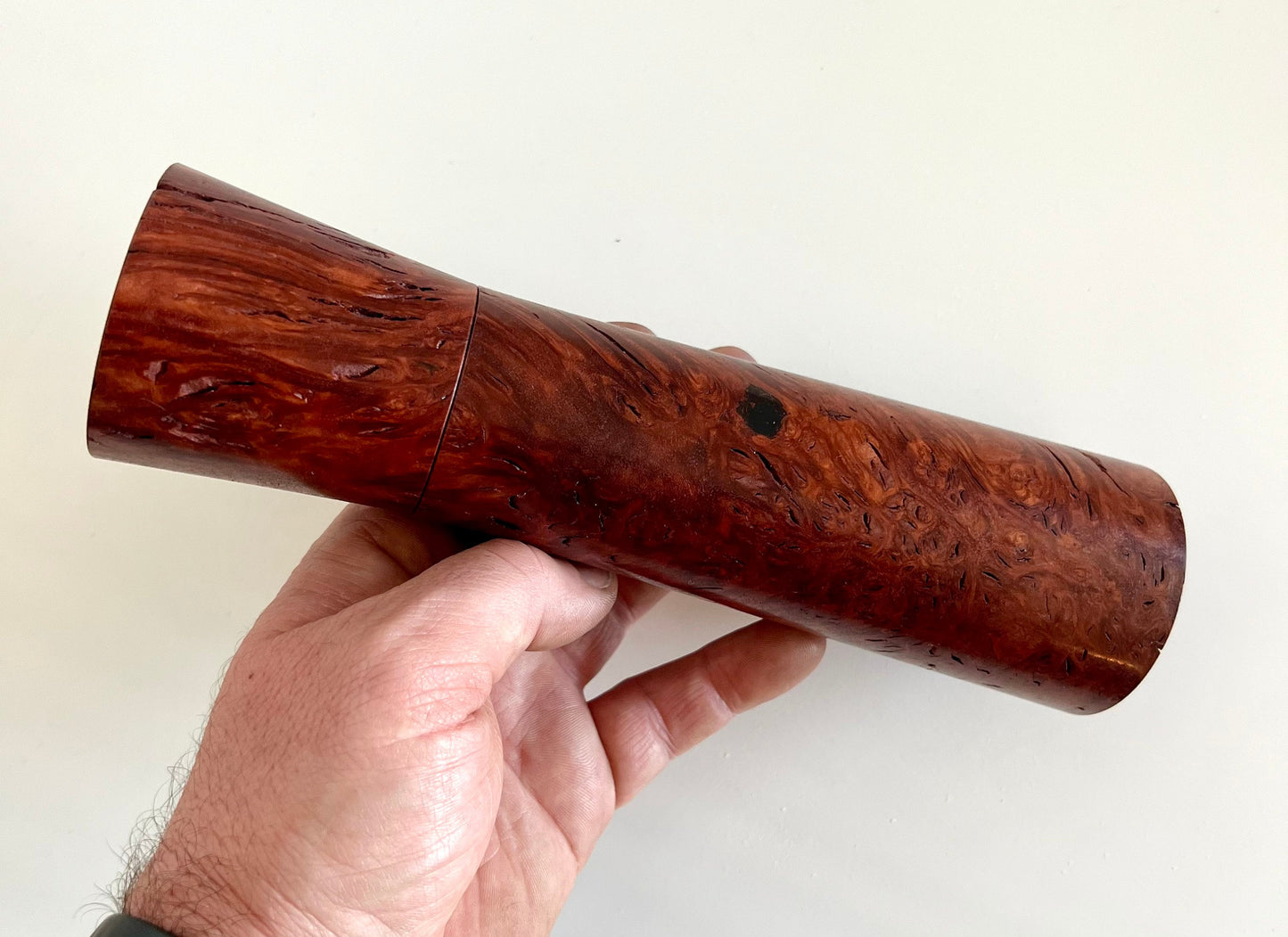 Mans hand holding single straight tapered Jarrah burl grinder.