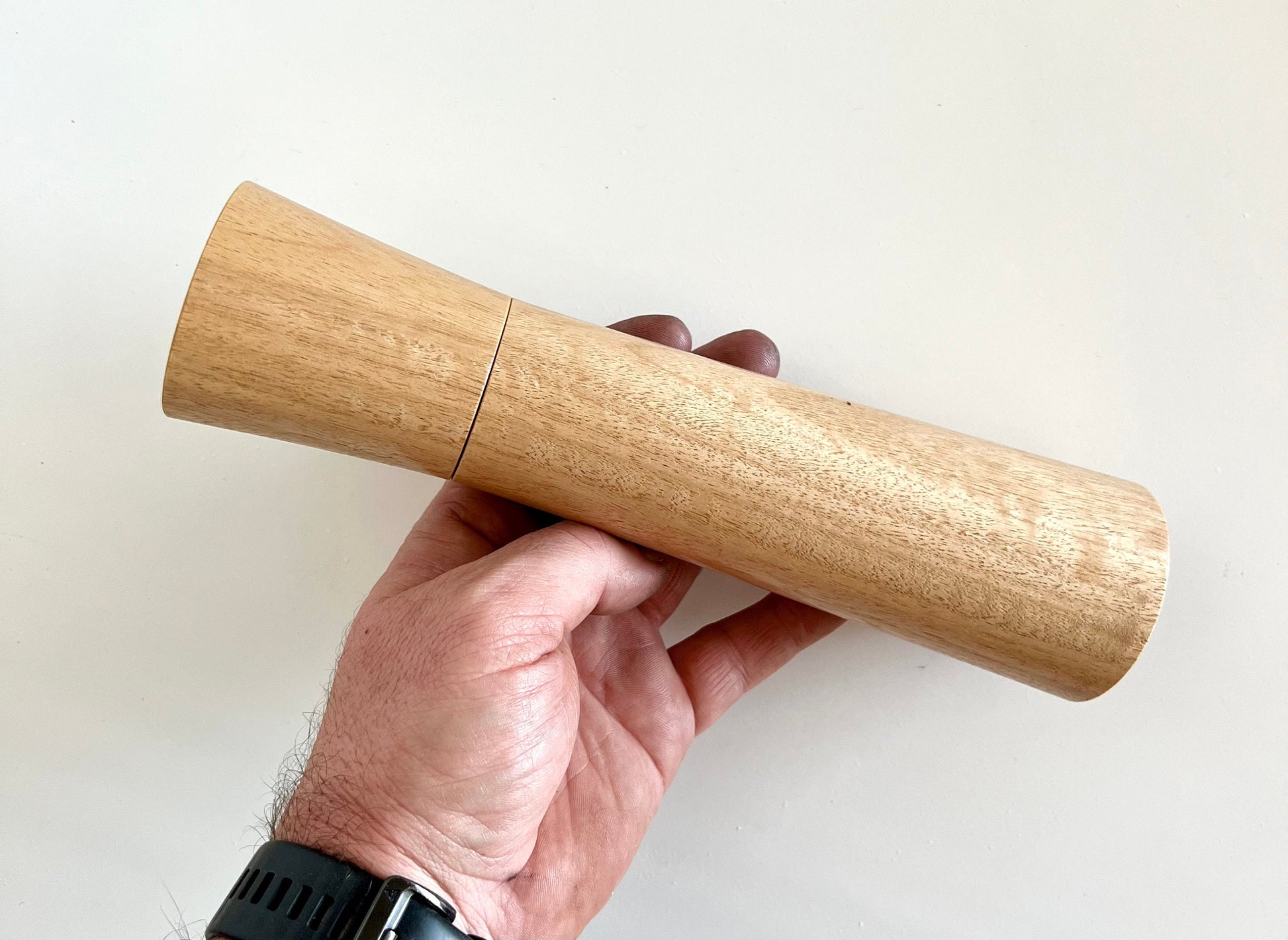 Mans hand holding single straight tapered Blackbutt grinder.