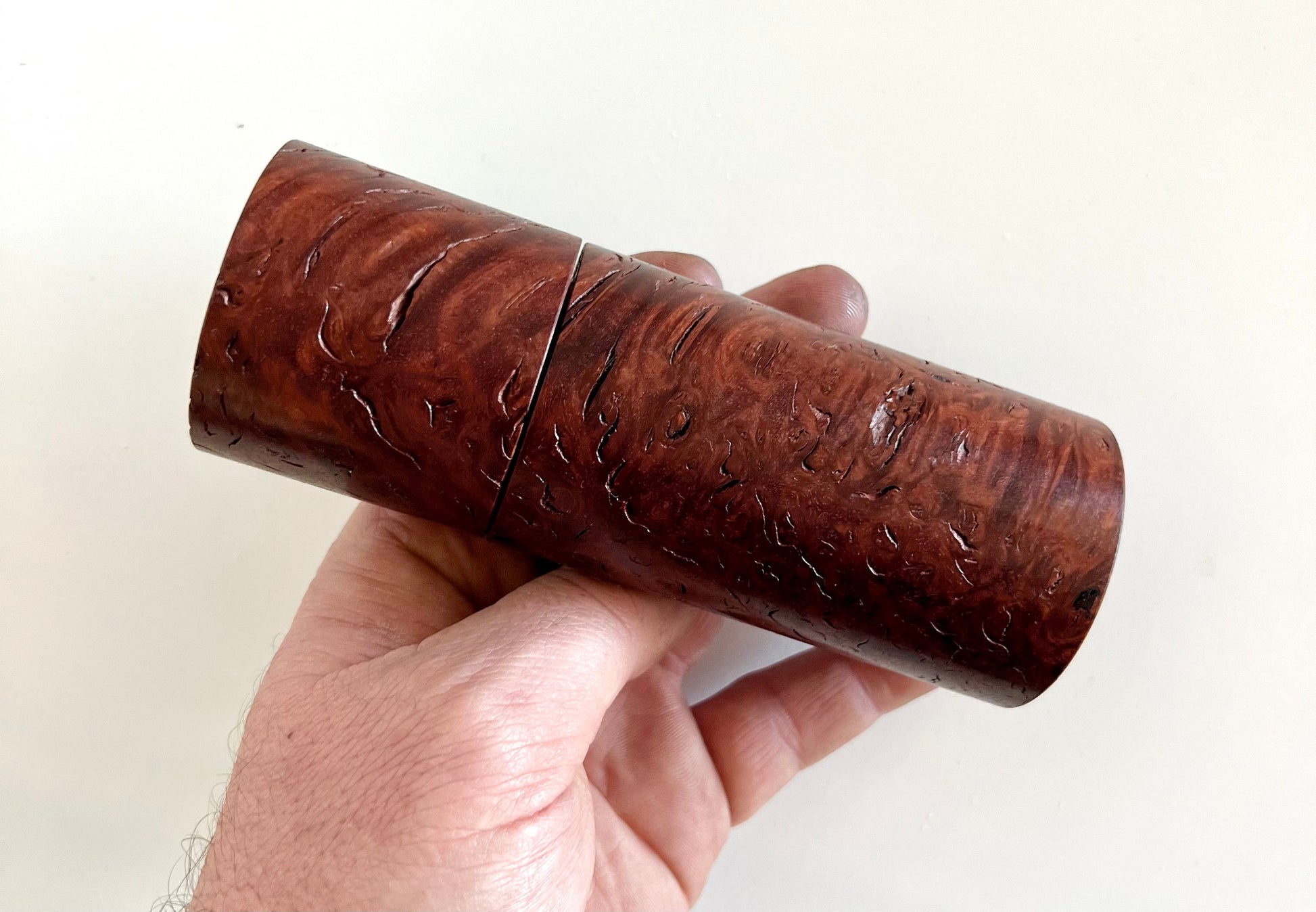 Mans hand holding single straight cylindrical jarrah burl grinder.