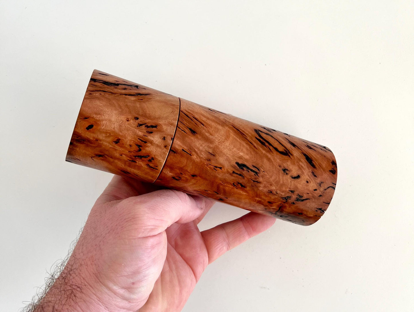 Mans hand holding single straight cylindrical Wandoo burl timber grinder