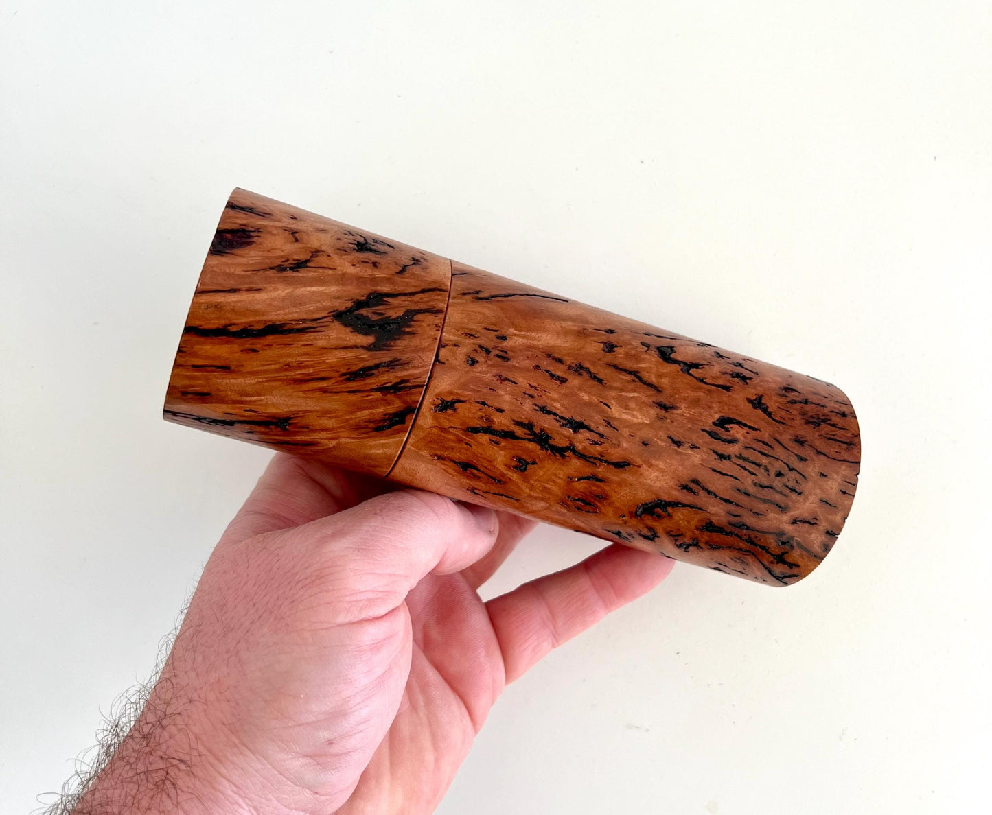 Mans hand holding single straight cylindrical Wandoo burl timber grinder