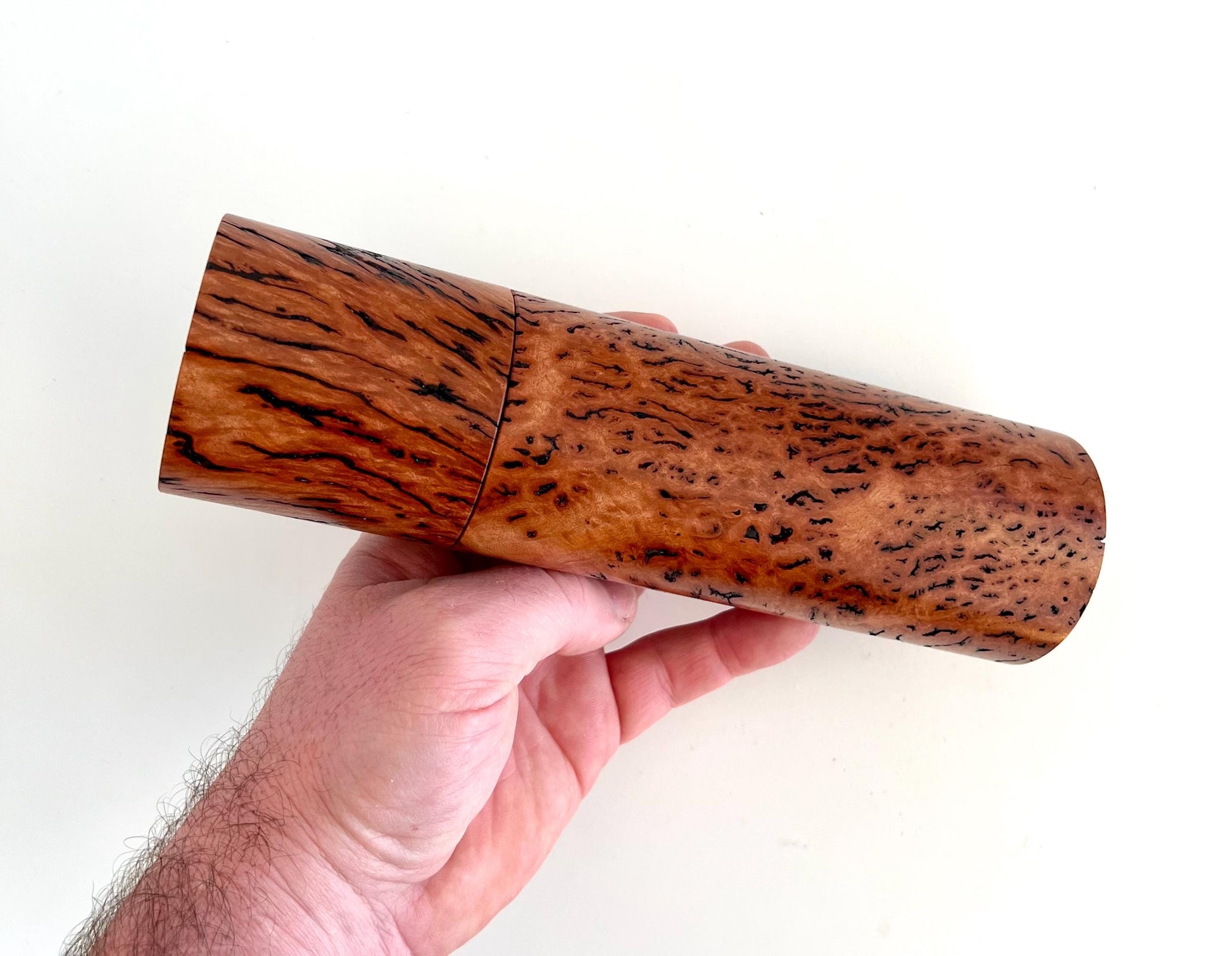 Mans hand holding single straight cylindrical Wandoo burl timber grinder