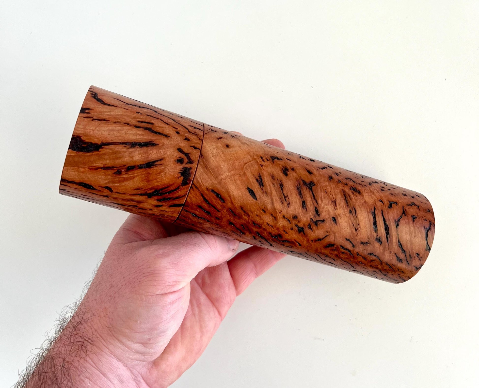 Mans hand holding single straight cylindrical Wandoo burl timber grinder