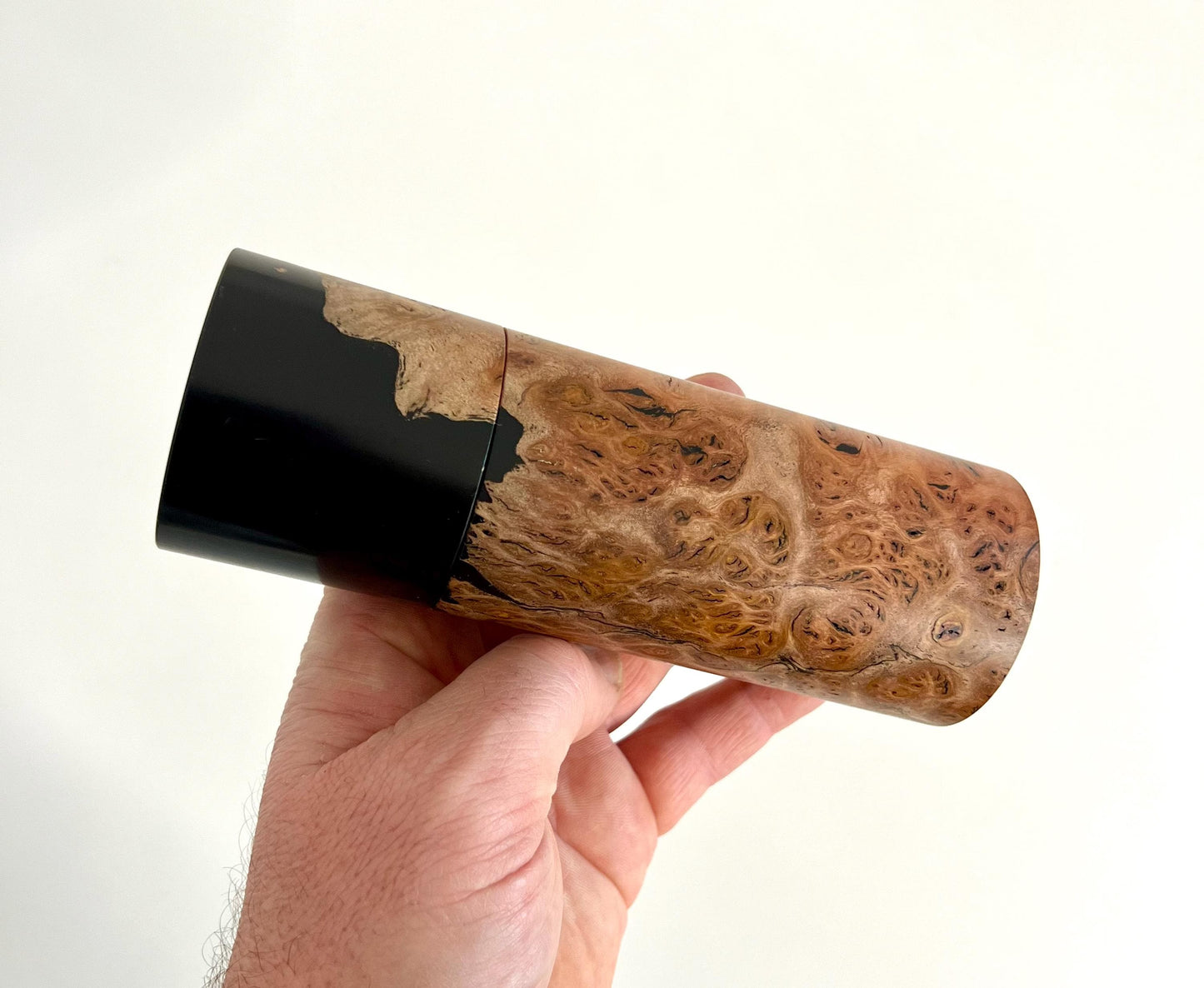 Mans hand holding single straight cylindrical Jarrah burl timber grinder