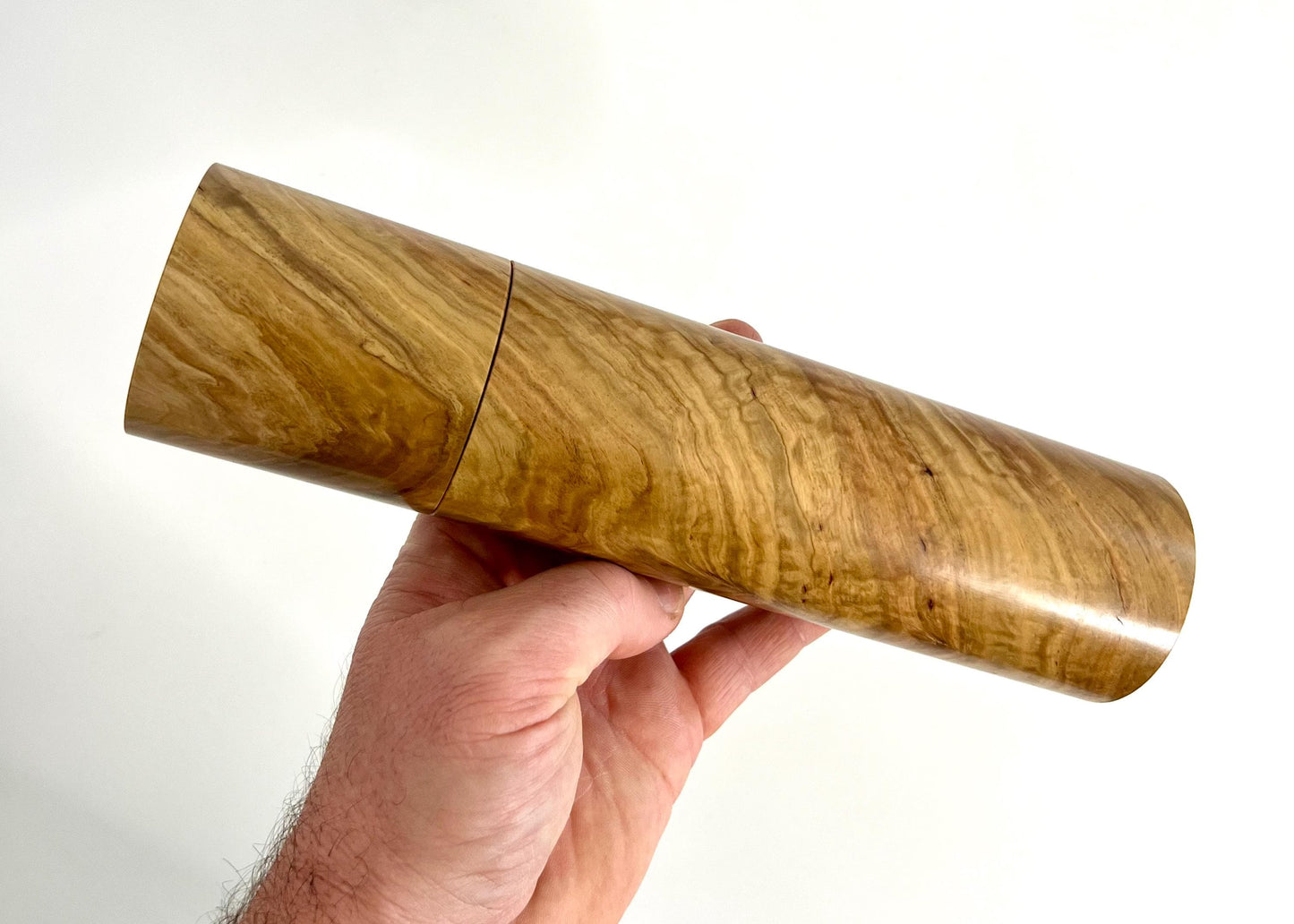 Mans hand holding single straight cylindrical Bimble Box Burl timber grinder