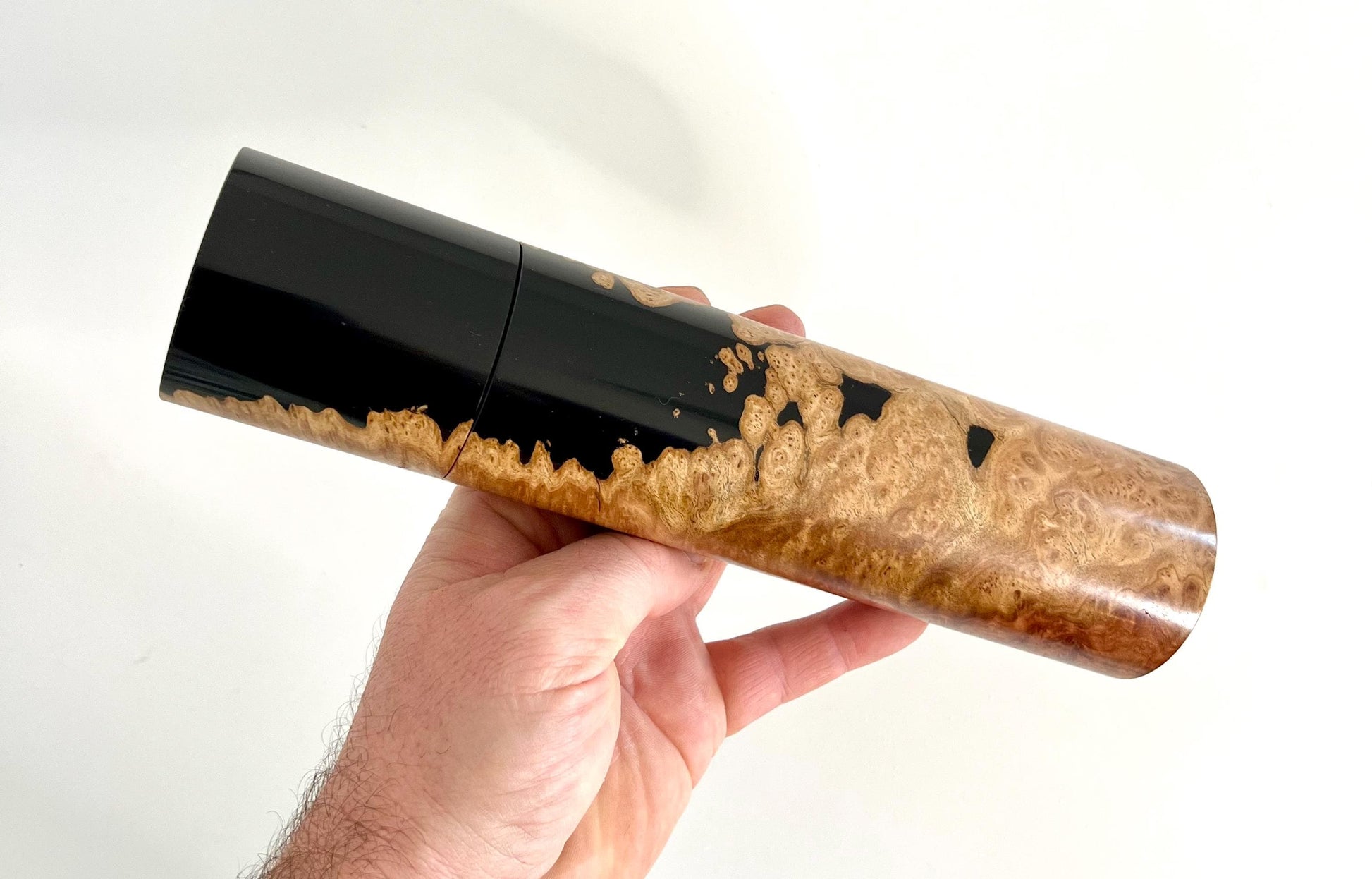 Mans hand holding single straight cylindrical burl timber grinder