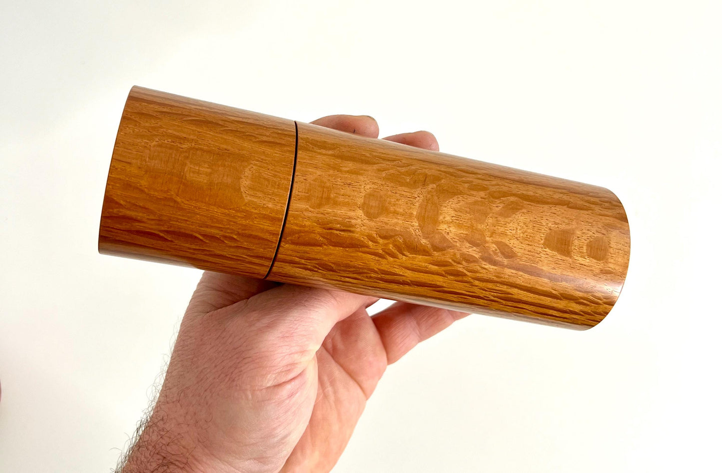 Mans hand holding single straight cylindrical Sheoak timber grinder