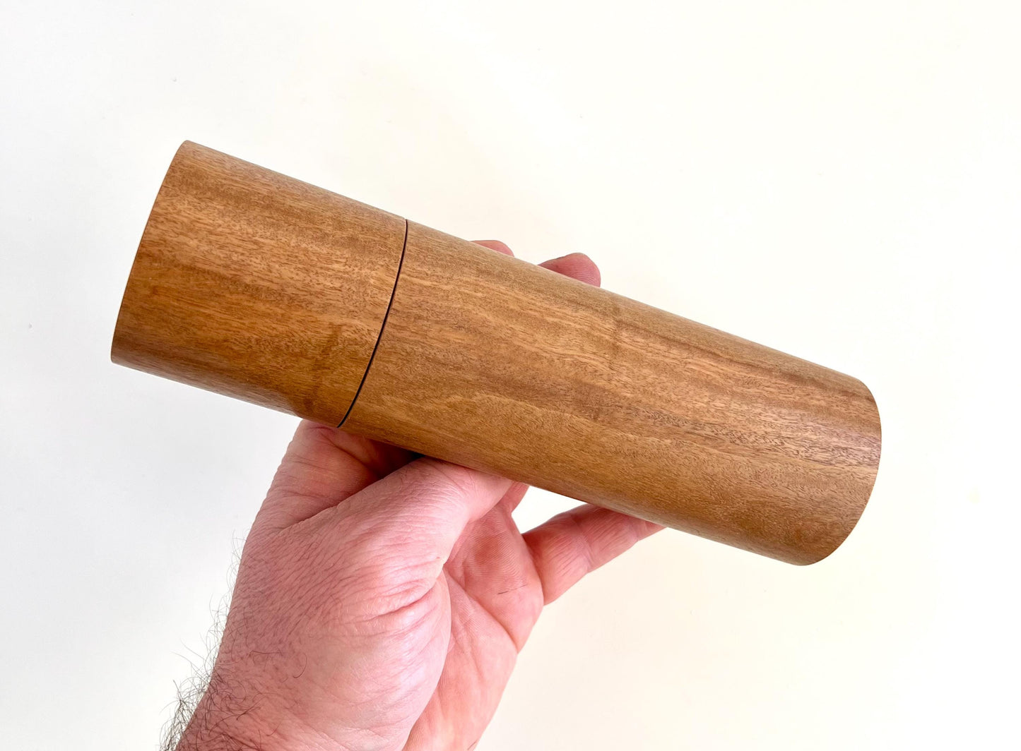 Mans hand holding single straight cylindrical Wandoo timber grinder