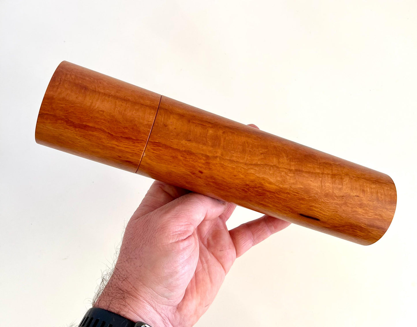 Mans hand holding single straight cylindrical Lace sheoak timber grinder