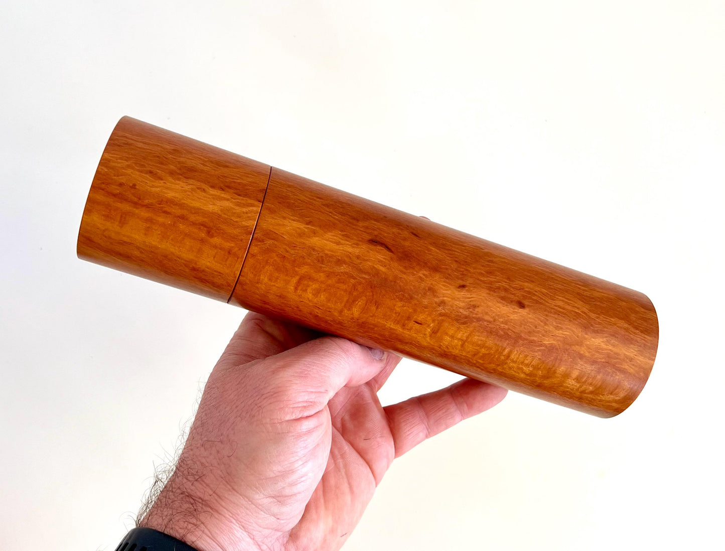 Mans hand holding single straight cylindrical Lace sheoak timber grinder