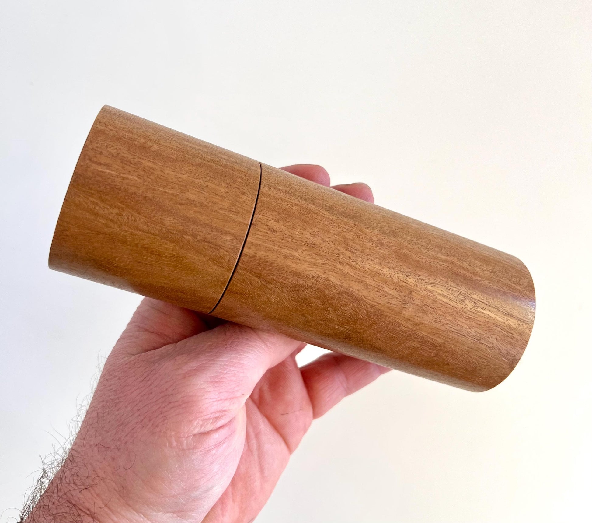 Mans hand holding single straight cylindrical Wandoo timber grinder