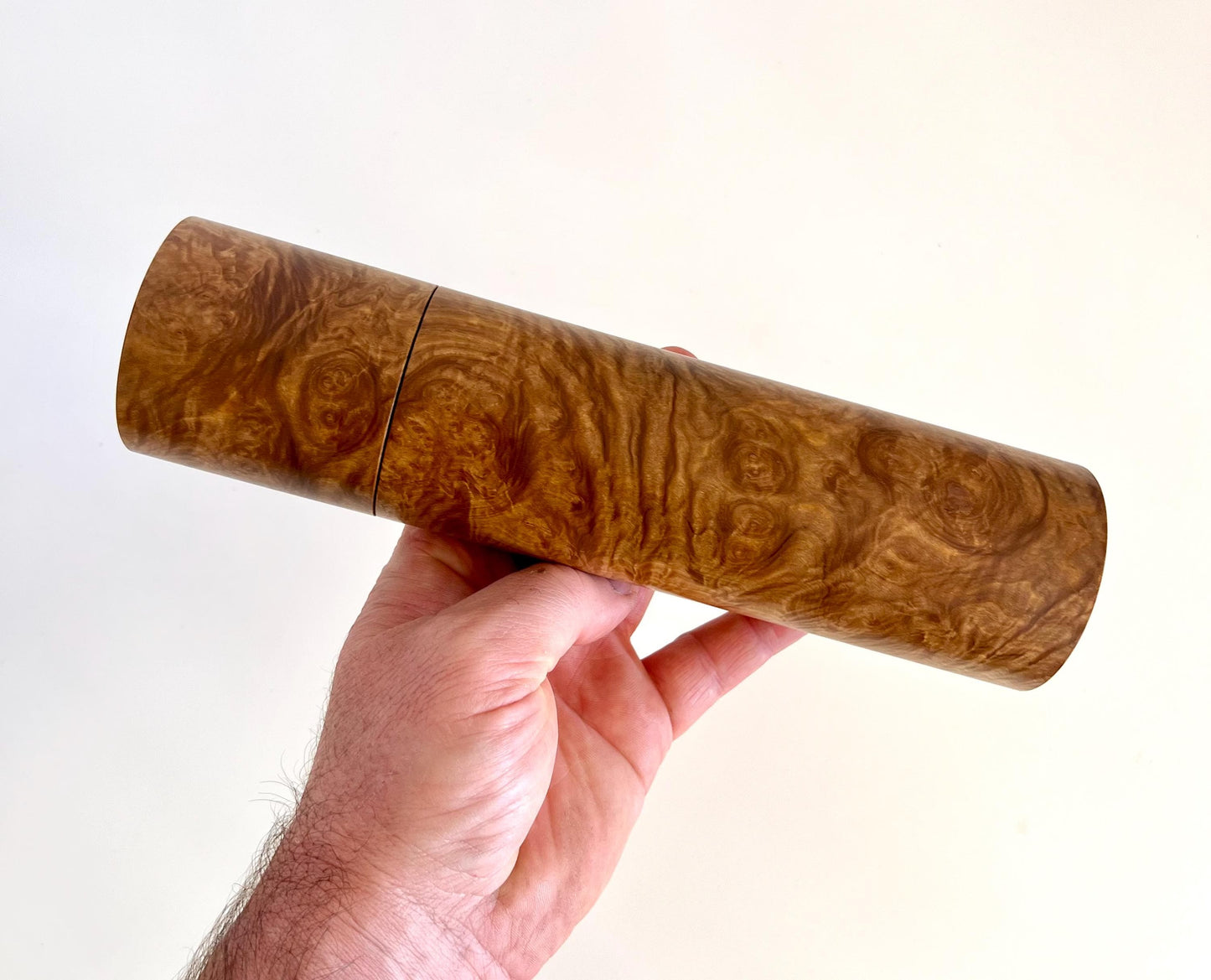 Mans hand holding single straight cylindrical Yorrell burl timber grinder