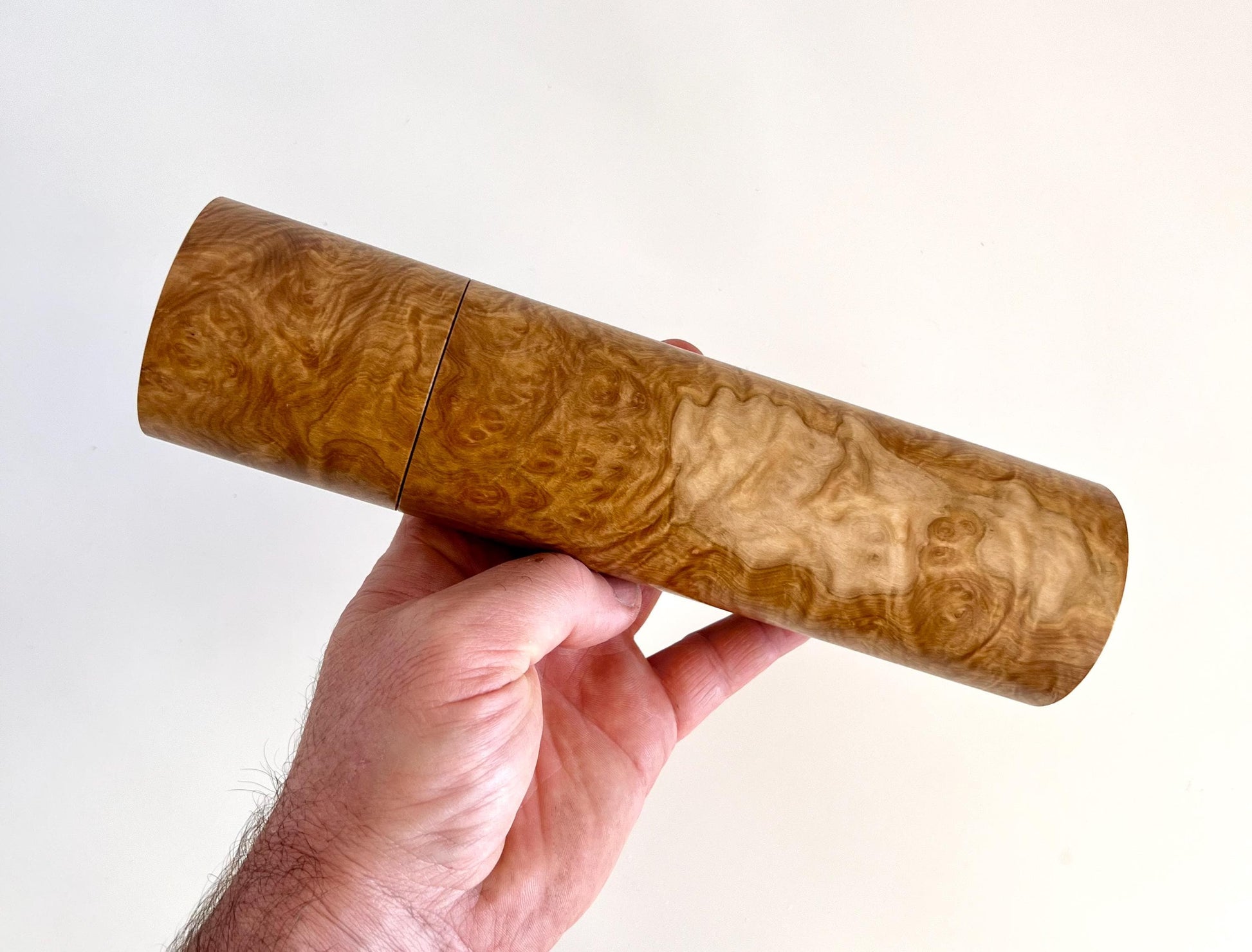 Mans hand holding single straight cylindrical Yorrell burl timber grinder