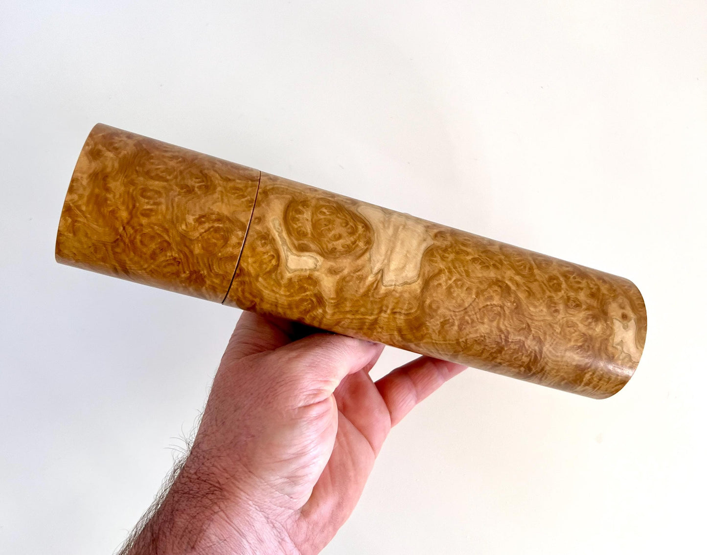 Mans hand holding single straight cylindrical Yorrell burl timber grinder