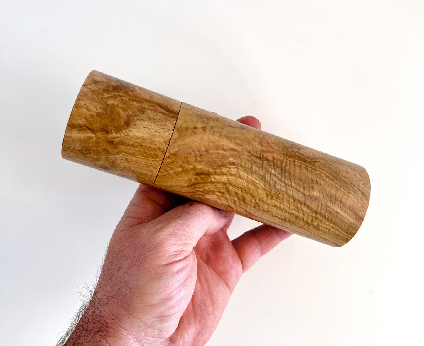 Mans hand holding single straight cylindrical Bimble box burl timber grinder