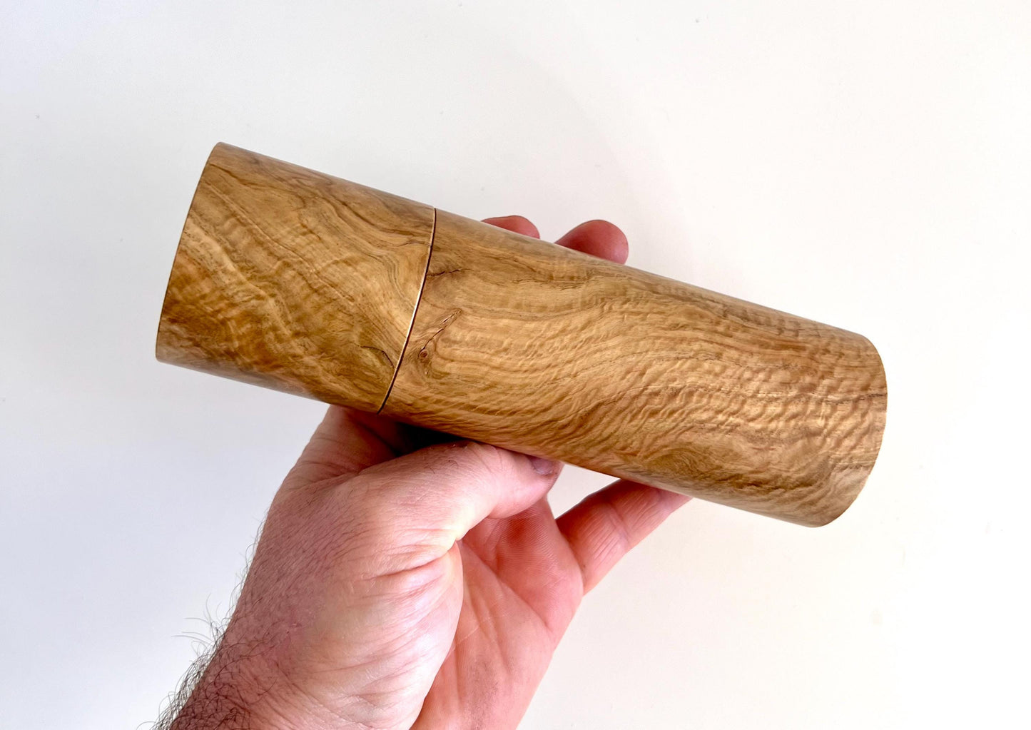 Mans hand holding single straight cylindrical Bimble box burl timber grinder