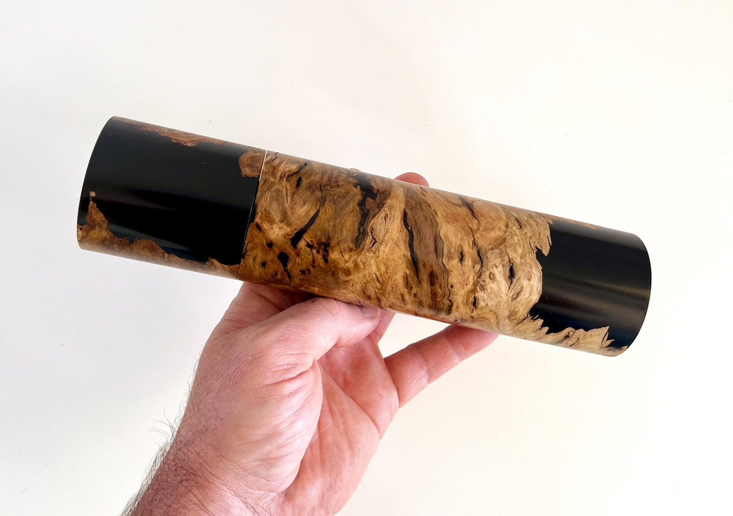 Mans hand holding single straight cylindrical Bimble box burl timber and black resin grinder