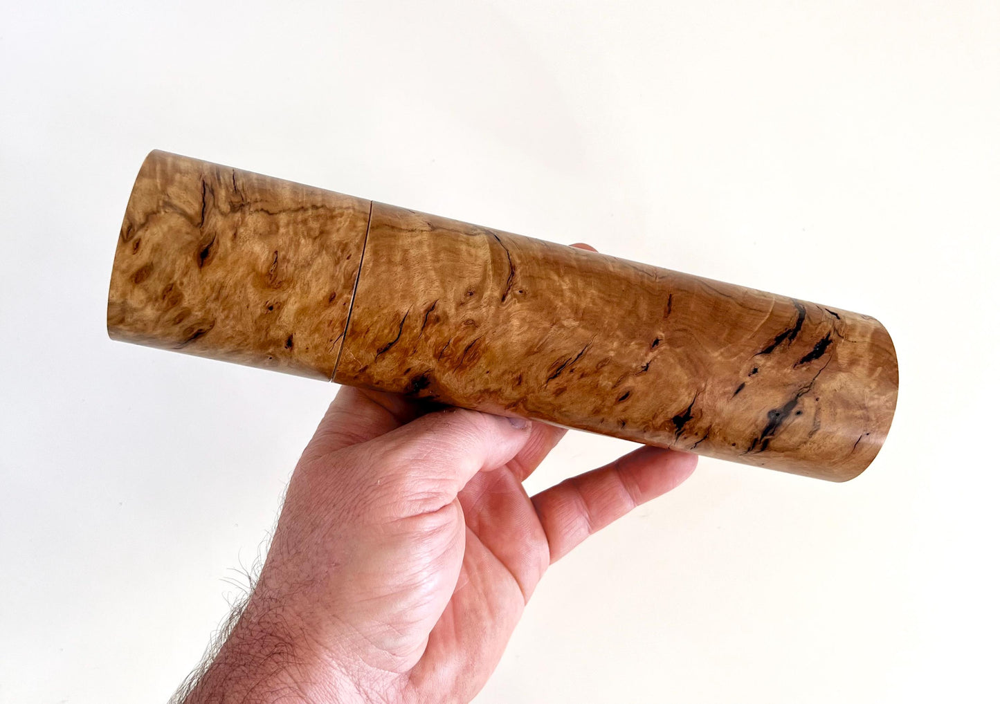 Mans hand holding single straight cylindrical Bimble box burl timber and black resin grinder