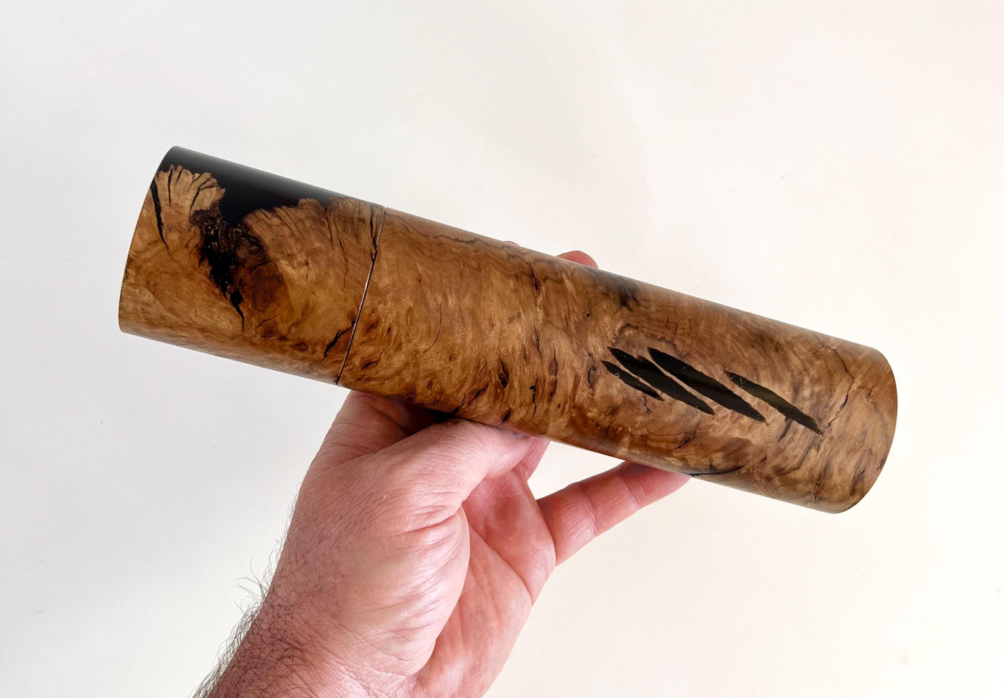 Mans hand holding single straight cylindrical Bimble box burl timber and black resin grinder