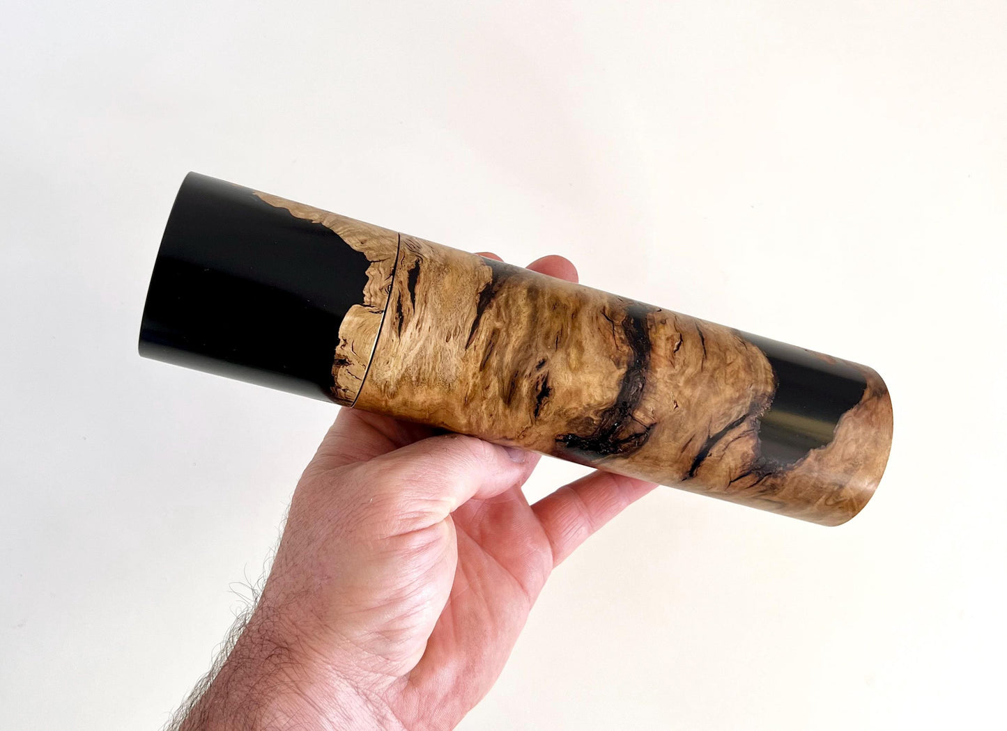 Mans hand holding single straight cylindrical Bimble box burl timber and black resin grinder