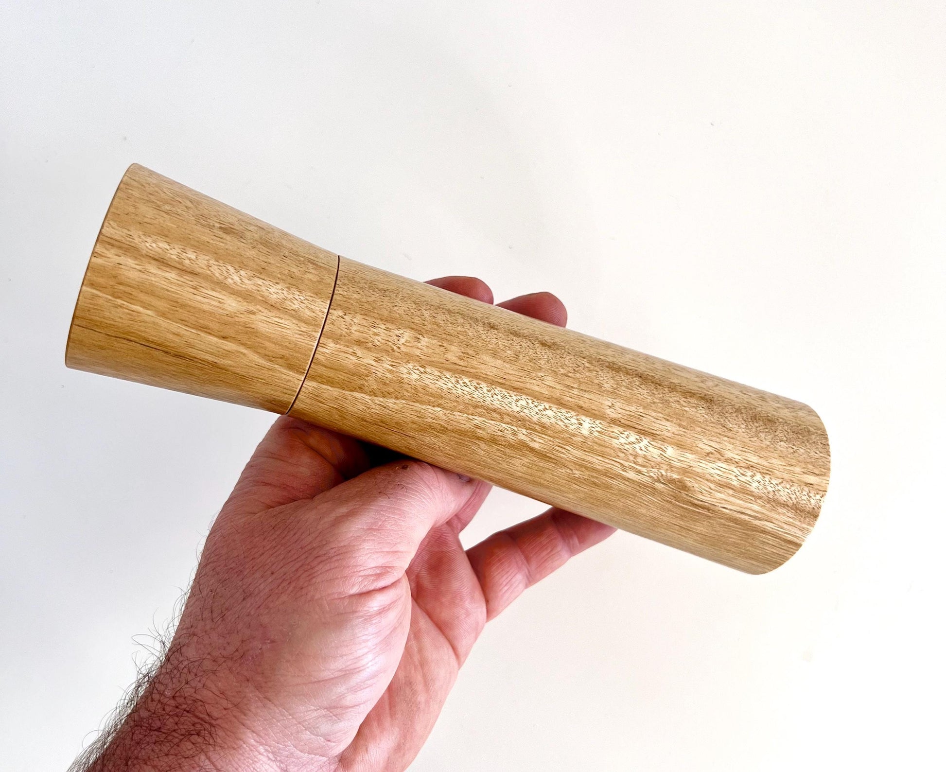 Mans hand holding single straight cylindrical bluegum timber grinder